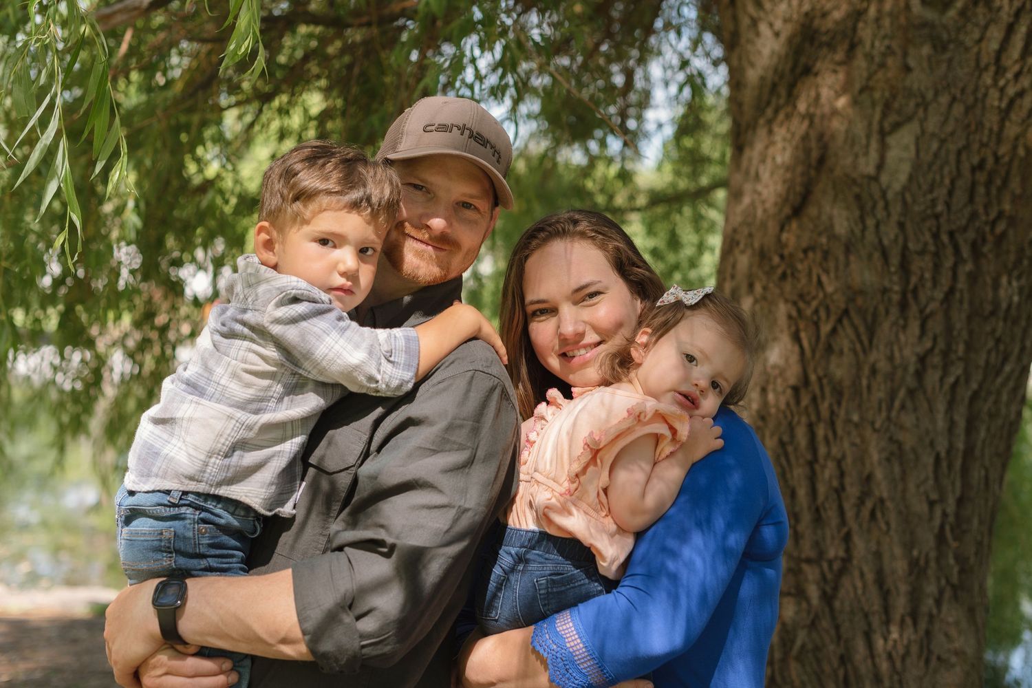 A loving family embraces outdoors near trees in a series of candid moments.
