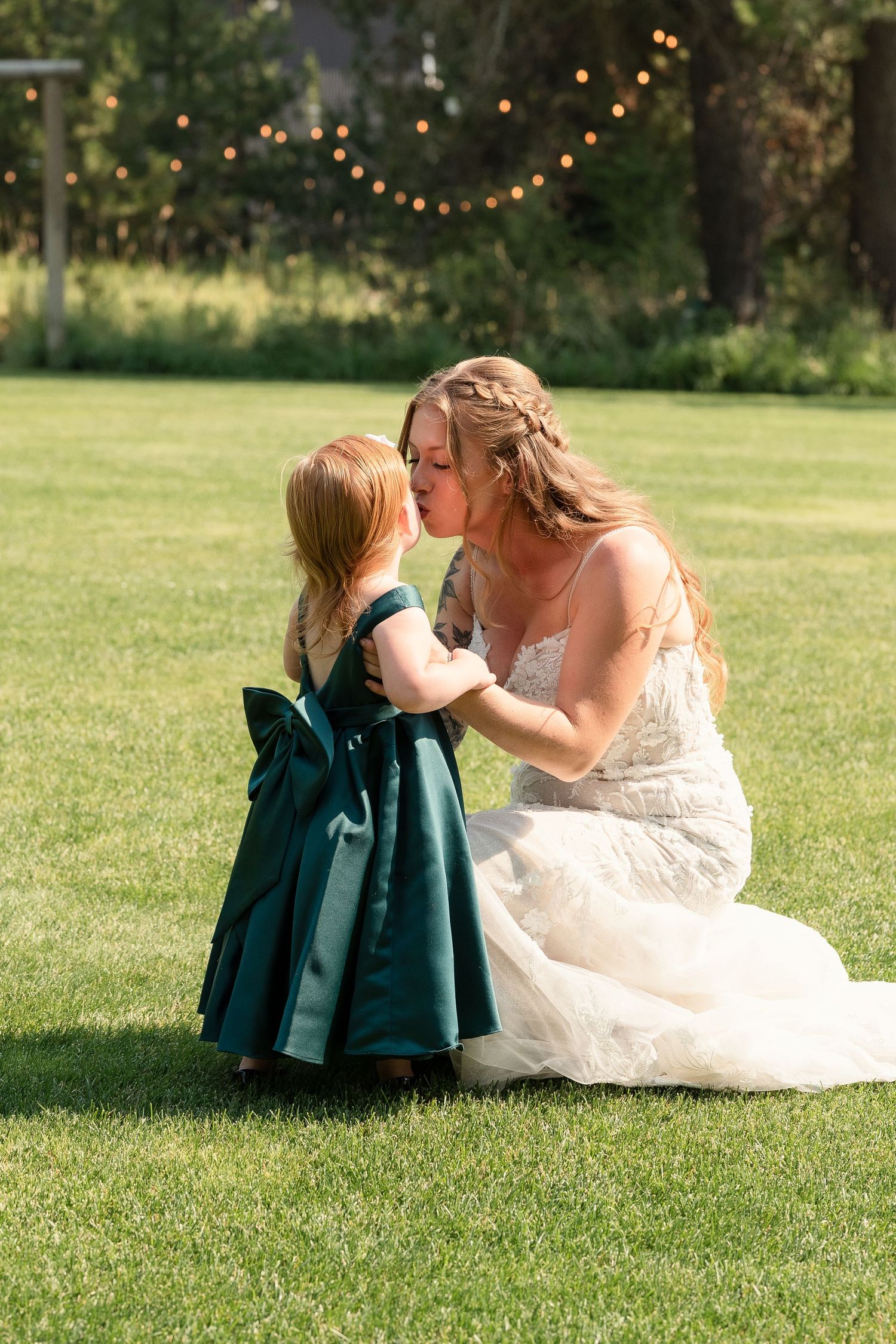Sweet outdoor wedding moment on a grassy lawn with string lights in the background.