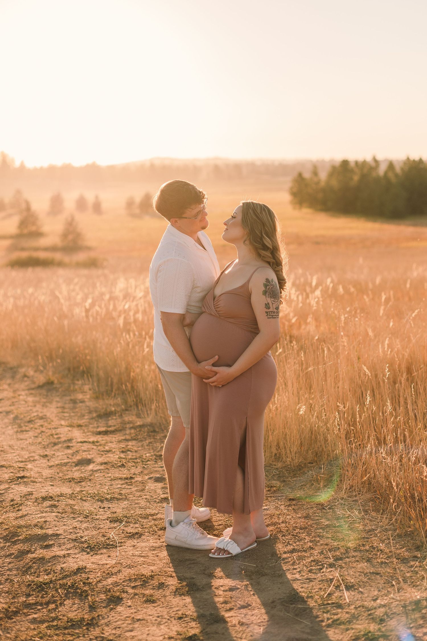 A couple shares an intimate moment in a golden wheat field at sunset.