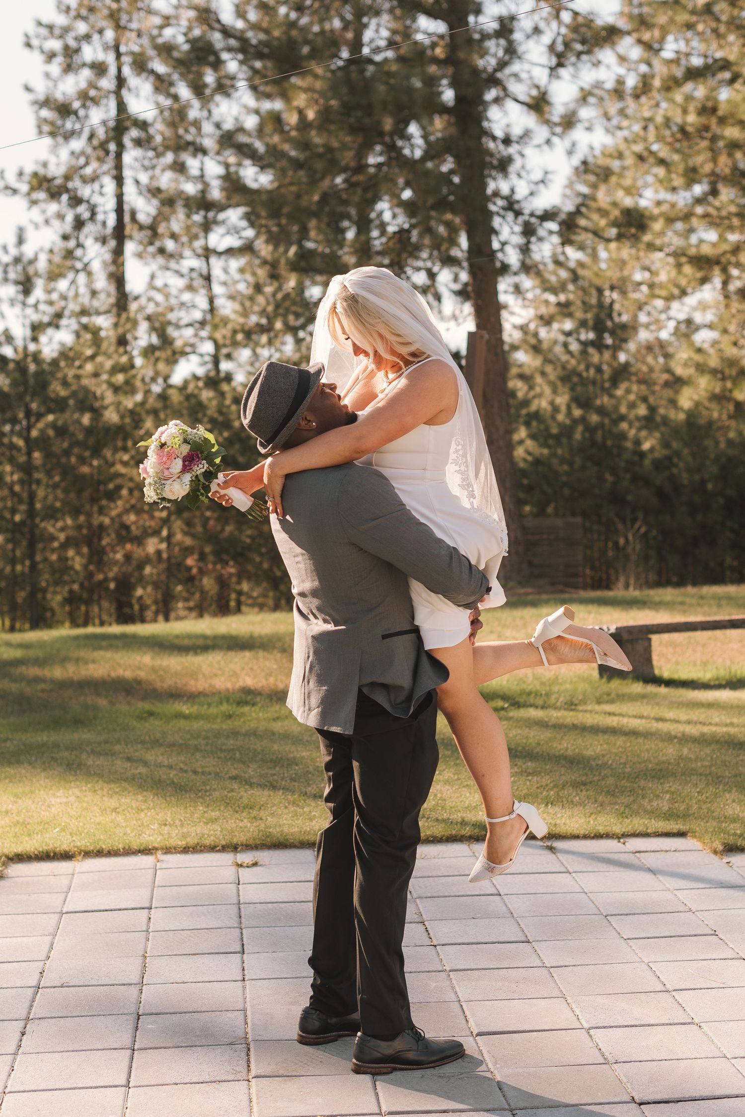 Playful wedding photo with pine trees and natural sunlight in background.