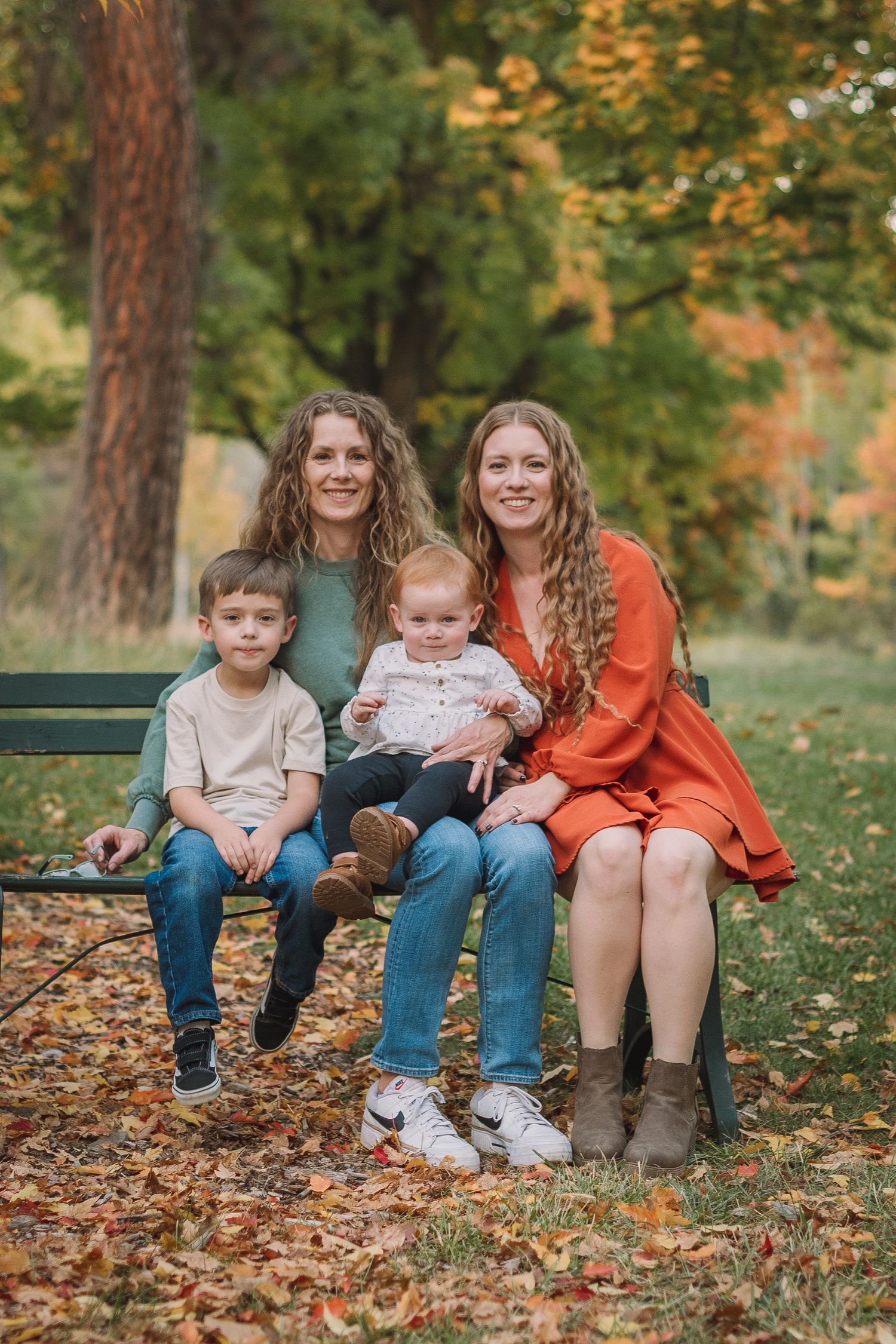 A heartwarming fall family portrait on a wooden bench surrounded by colorful autumn foliage.