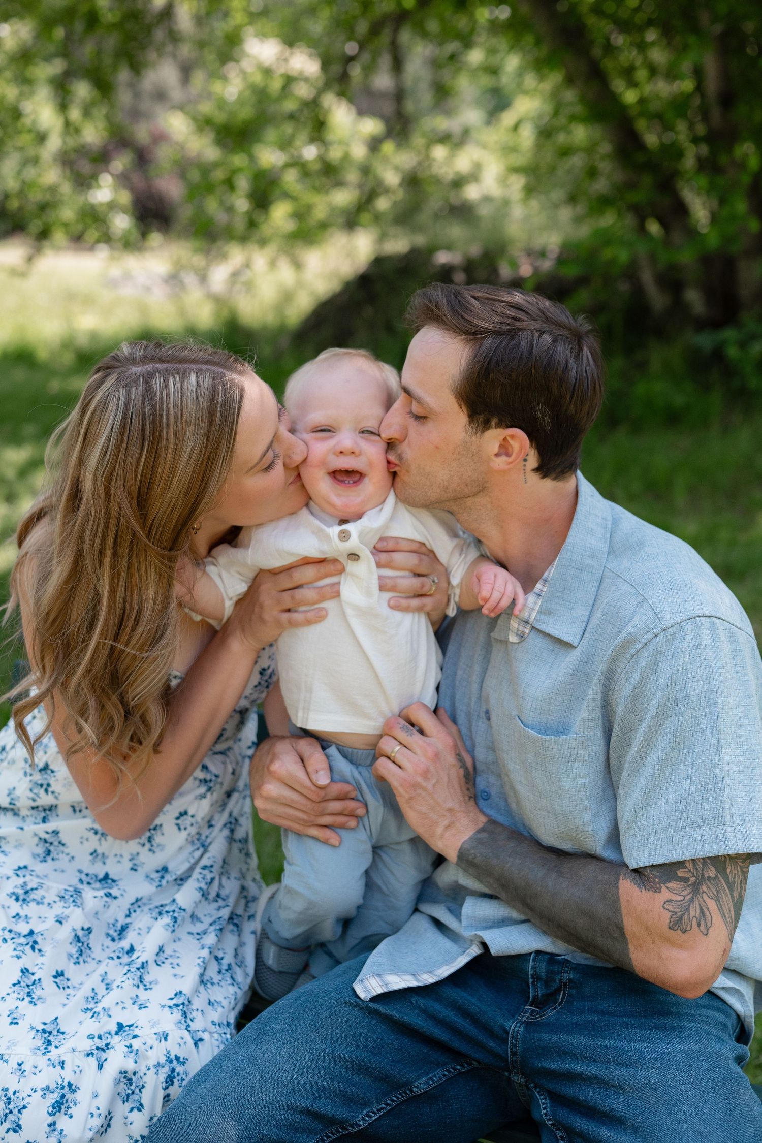 A happy family shares joyful kisses and laughter with their baby in a series of outdoor portraits.