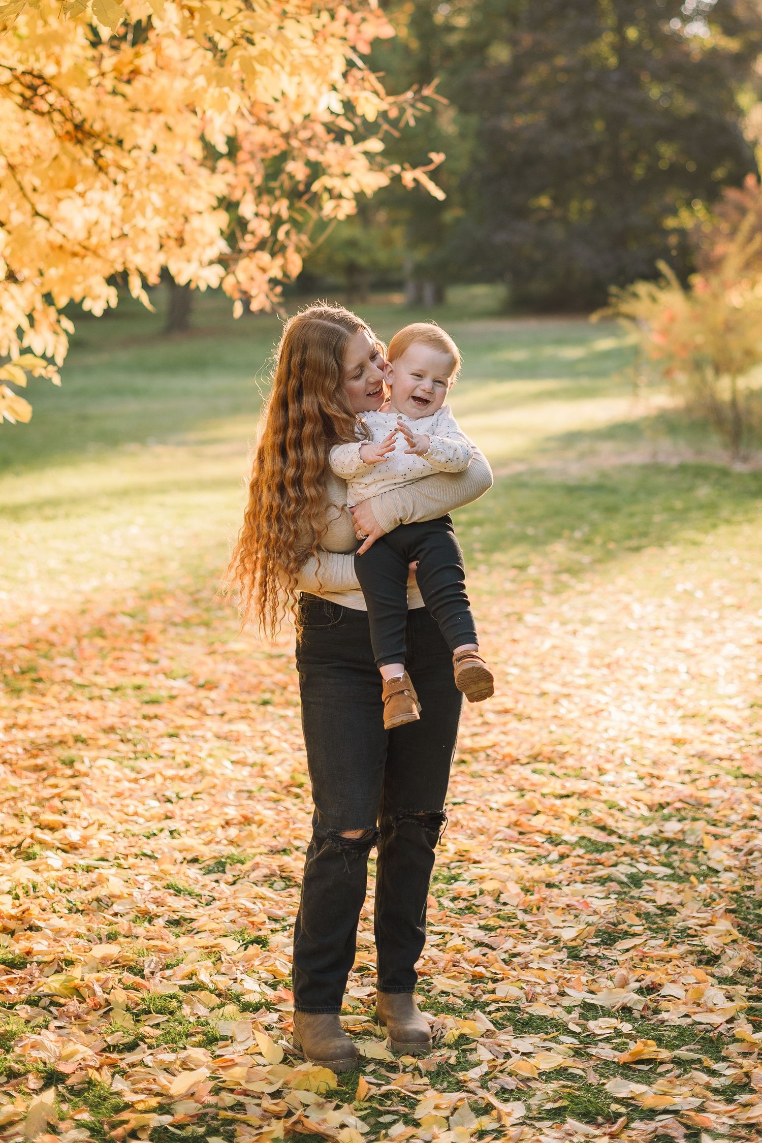 A tender autumn moment captured in a park with fallen golden leaves and warm sunlight filtering through trees.