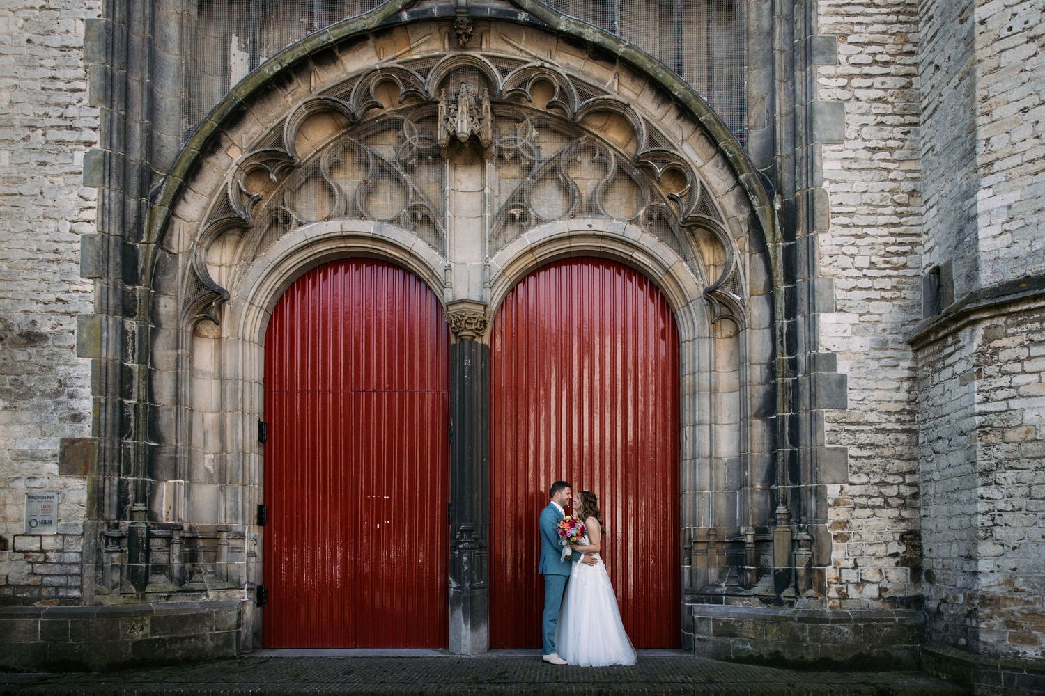 bruidspaar samen voor een deur van de hooglandse kerk in leiden
