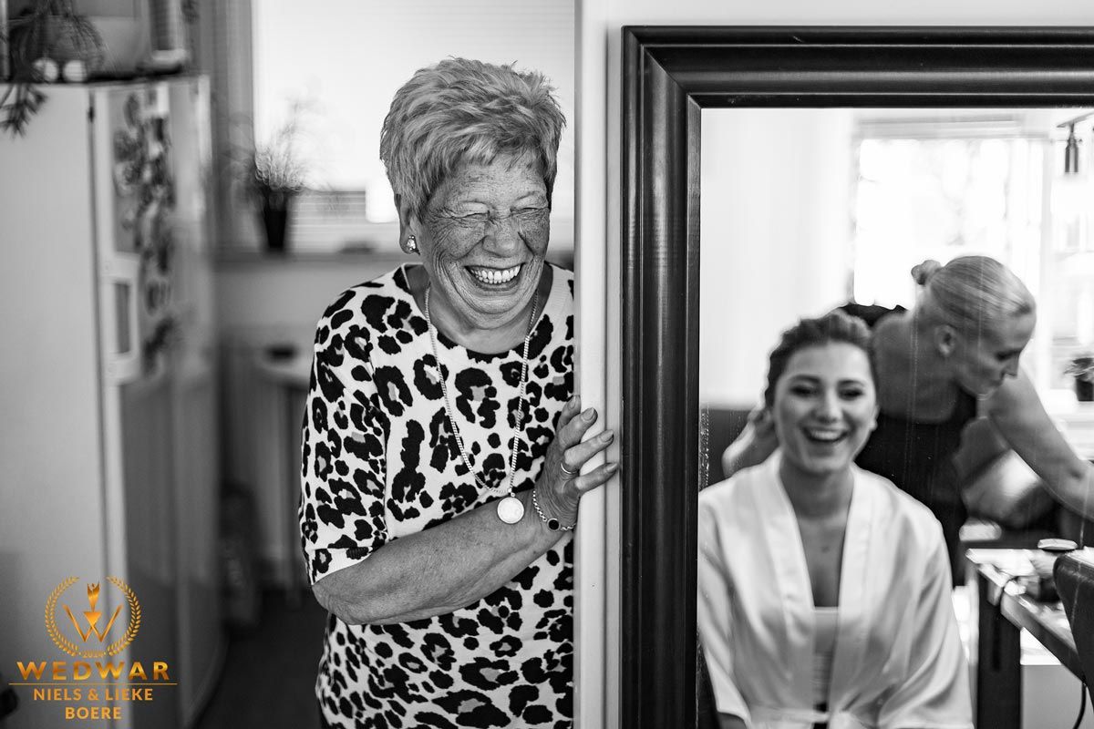 oma die trots kijkt naar kleindochter die je in de spiegel ziet zitten, oma lacht