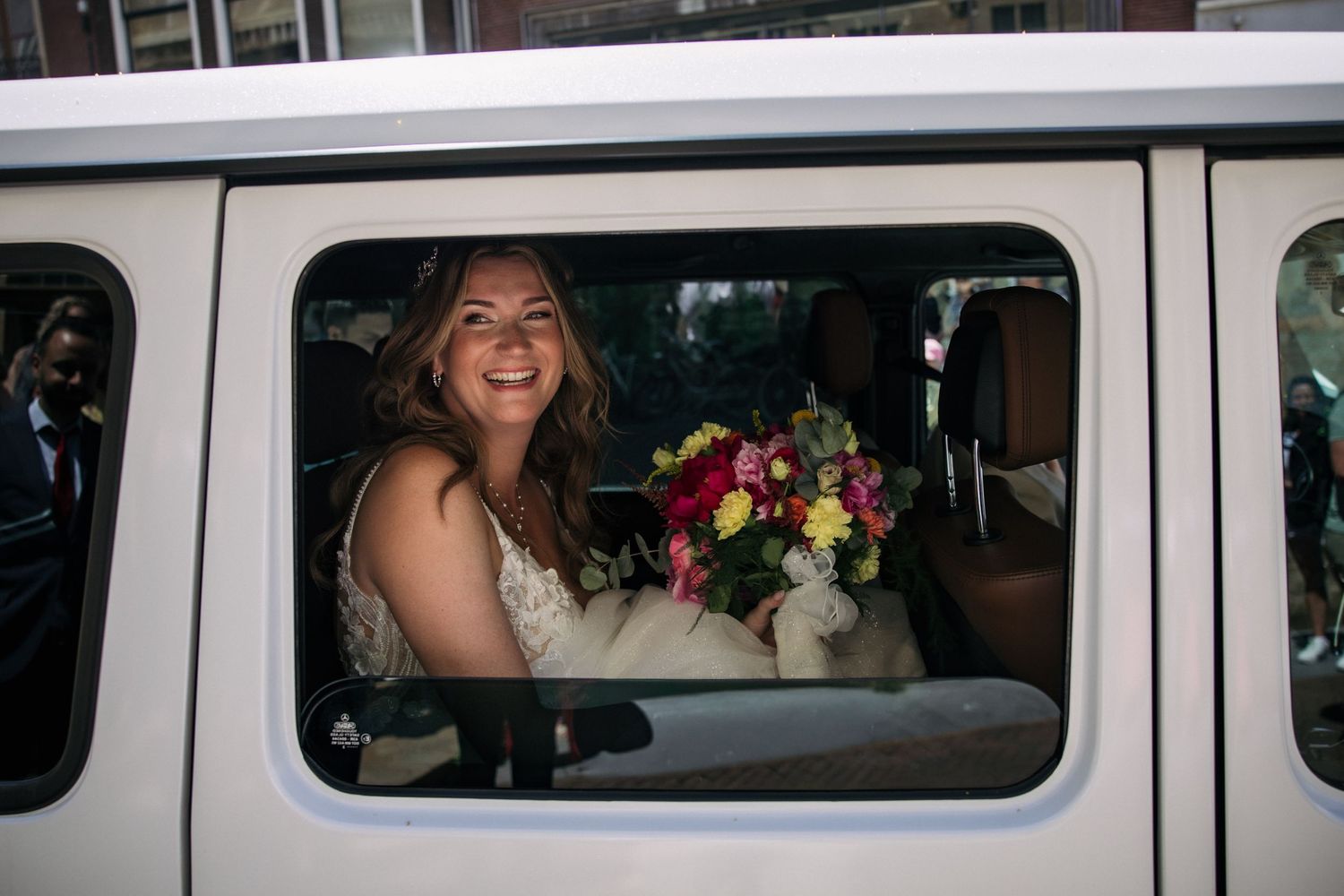 bruid in mercedes g klasse door het raam met bloemen