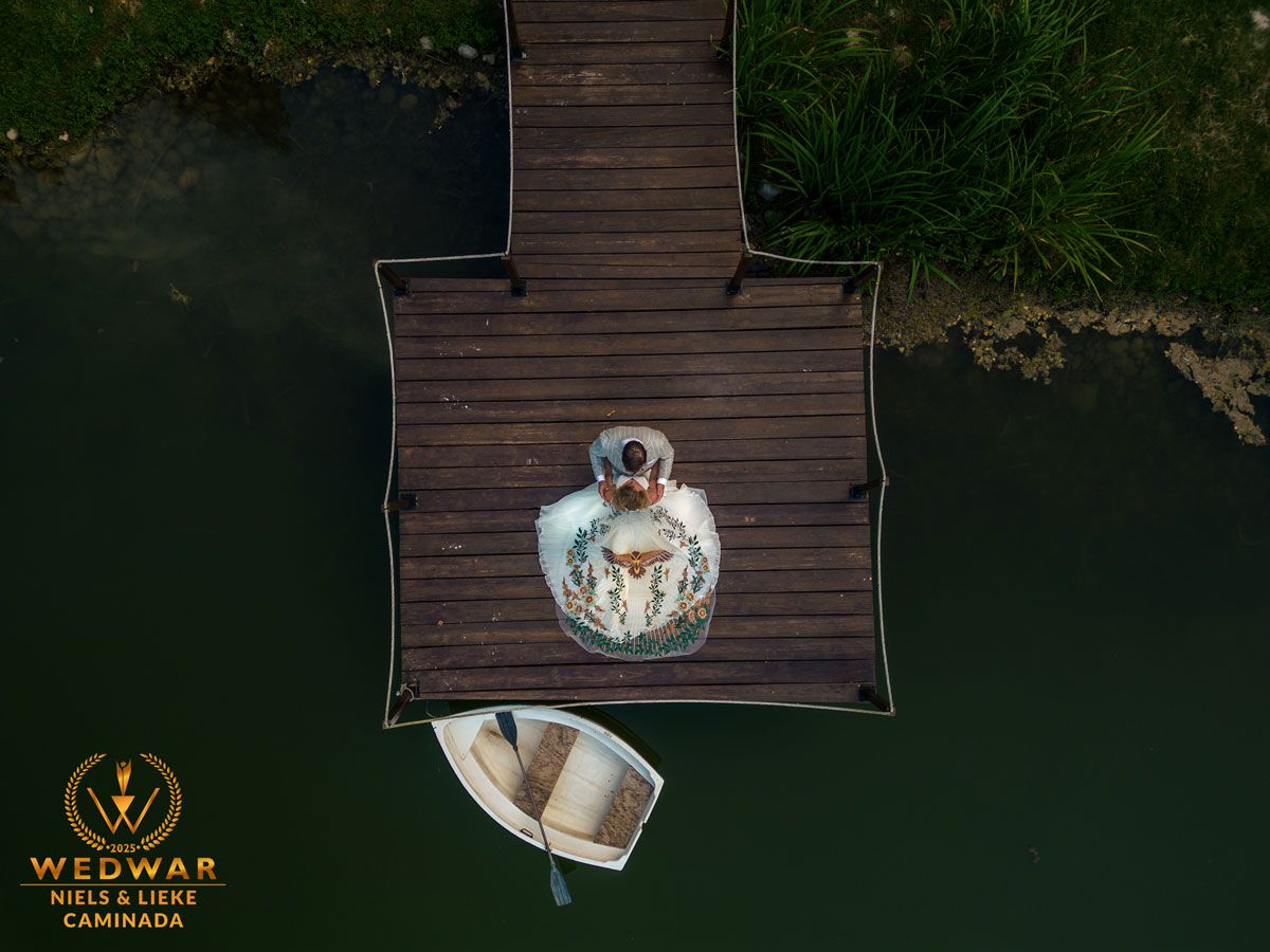 drone foto van bruidspaar op een steiger met een bijzondere sluier en boot