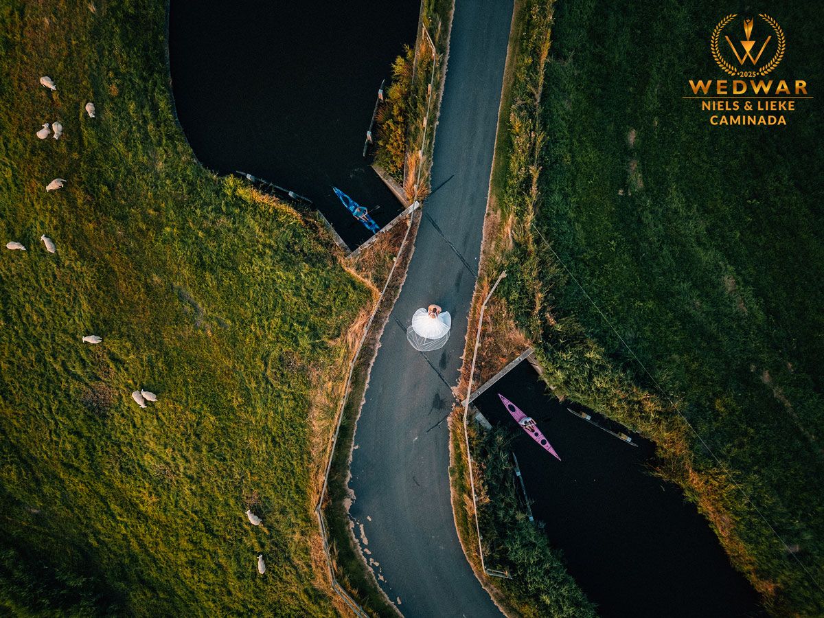 drone foto van bruidspaar in friesland op een brug met een kano er bij