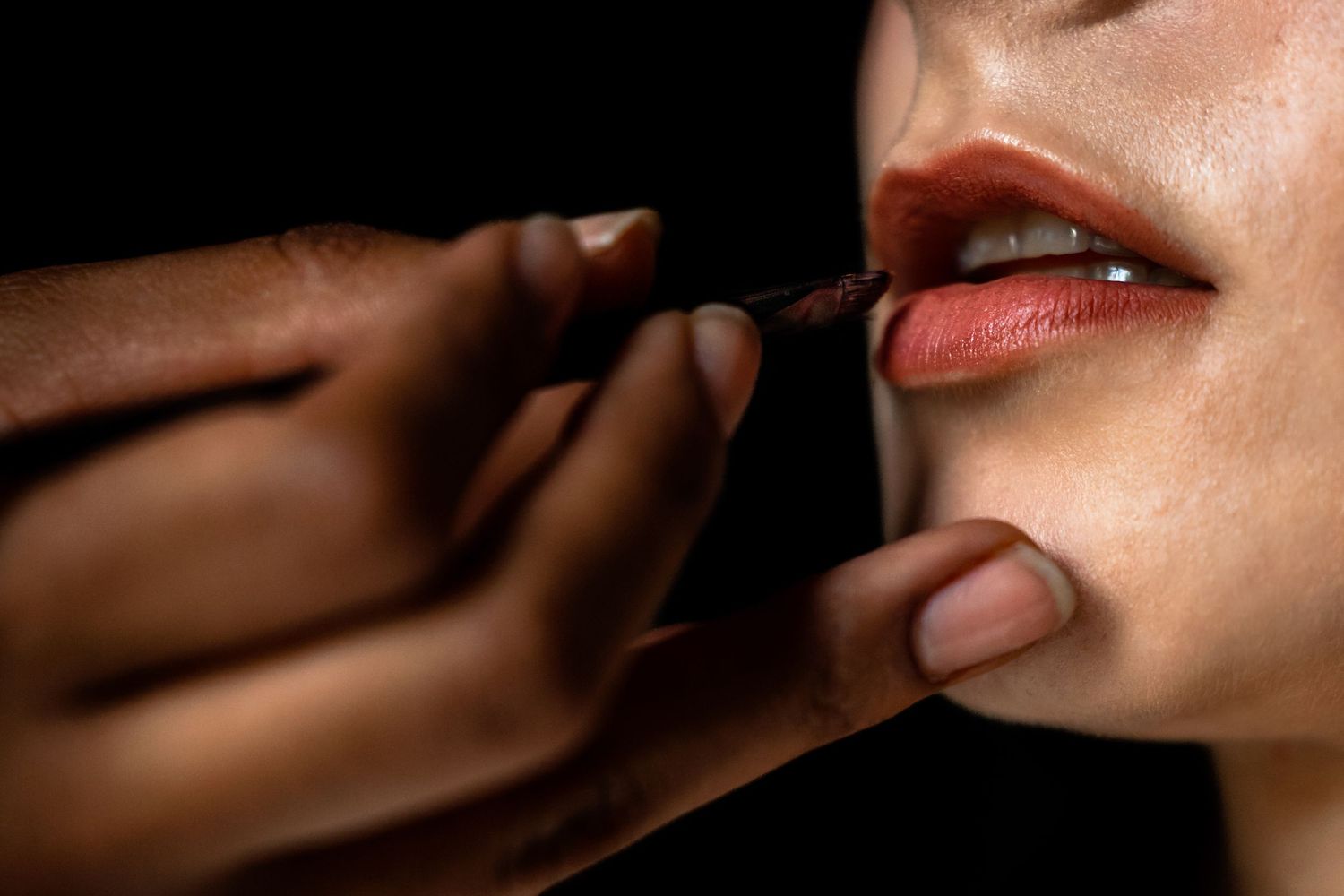 close up foto van een hand die lippenstift aanbrengt bij een bruid