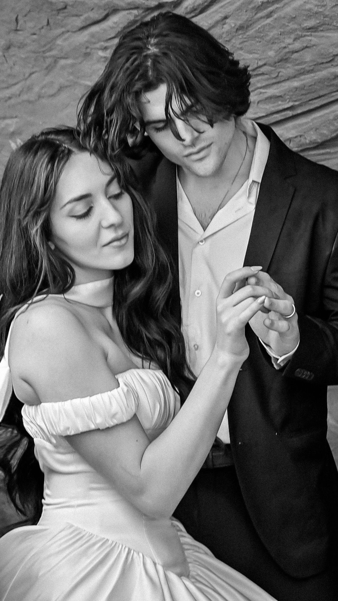 A romantic black and white photo of a couple dancing, with the woman in a stunning off the shoulder wedding gown and the man in a dark suit.