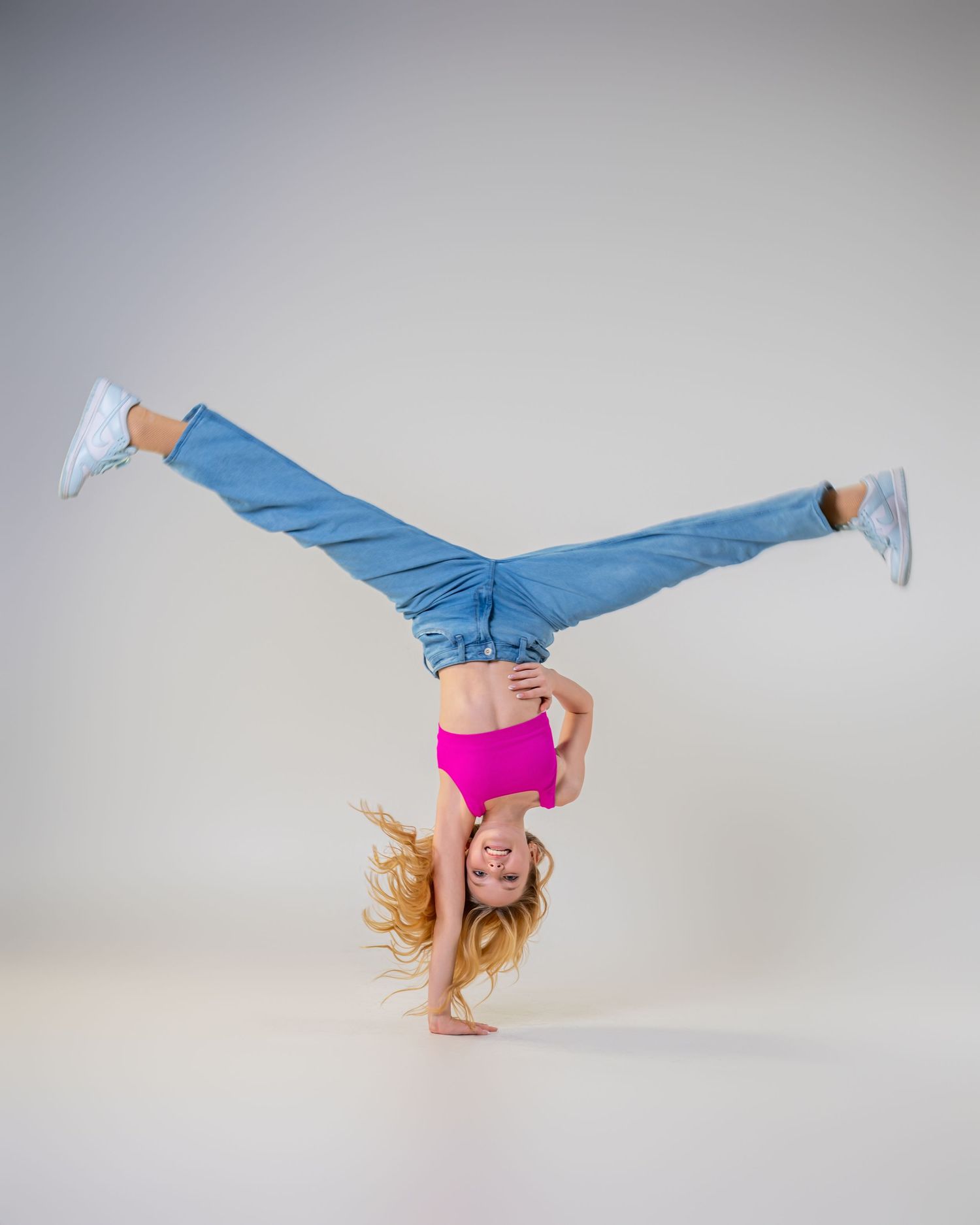 Omaha Senior Photography - Photographer in Omaha - A dancer in blue jeans and a pink top performs a dynamic one-handed cartwheel.