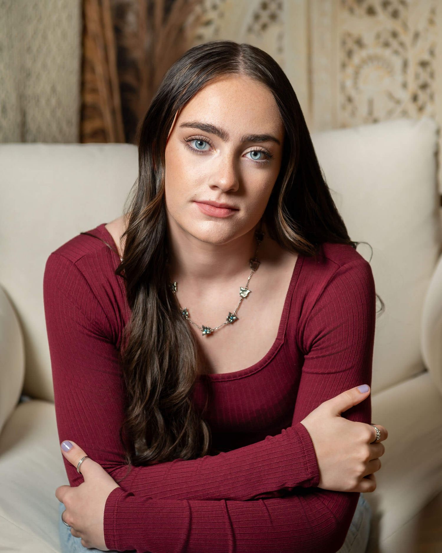 Portrait series showing a woman in a burgundy top posing on a light colored couch.