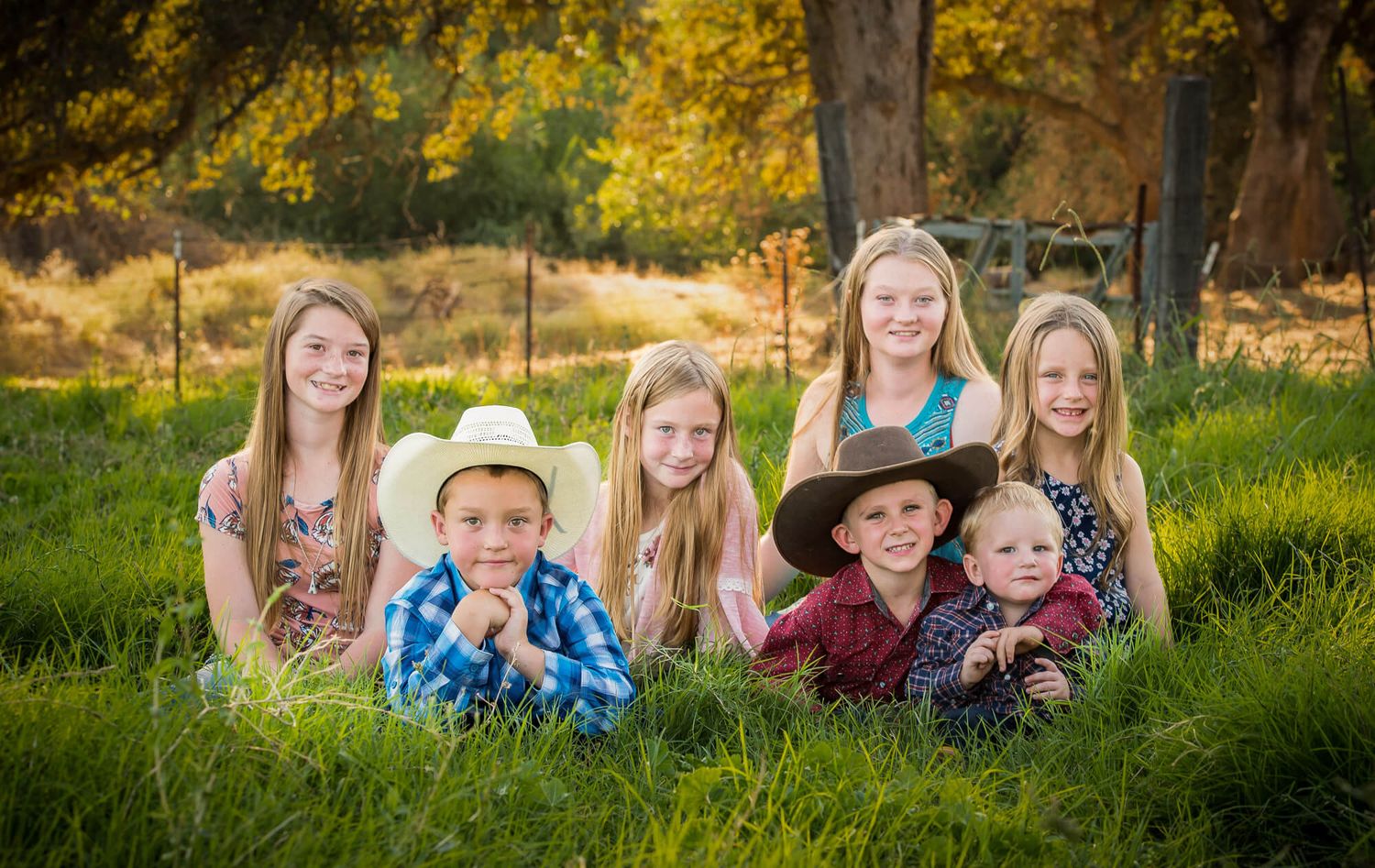 Group of people sitting together in lush green grass during golden hour sunset.