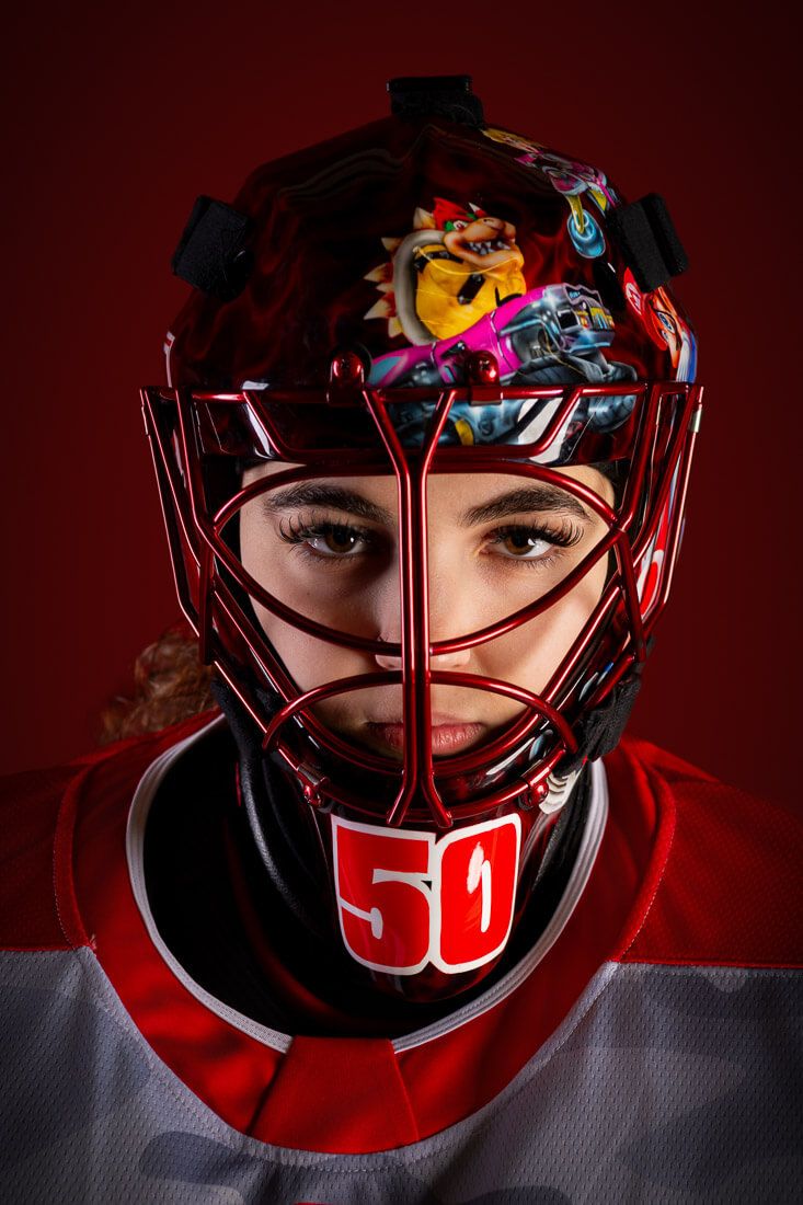 A series of dramatic close-up shots of a red hockey goalie mask against a dark background.
