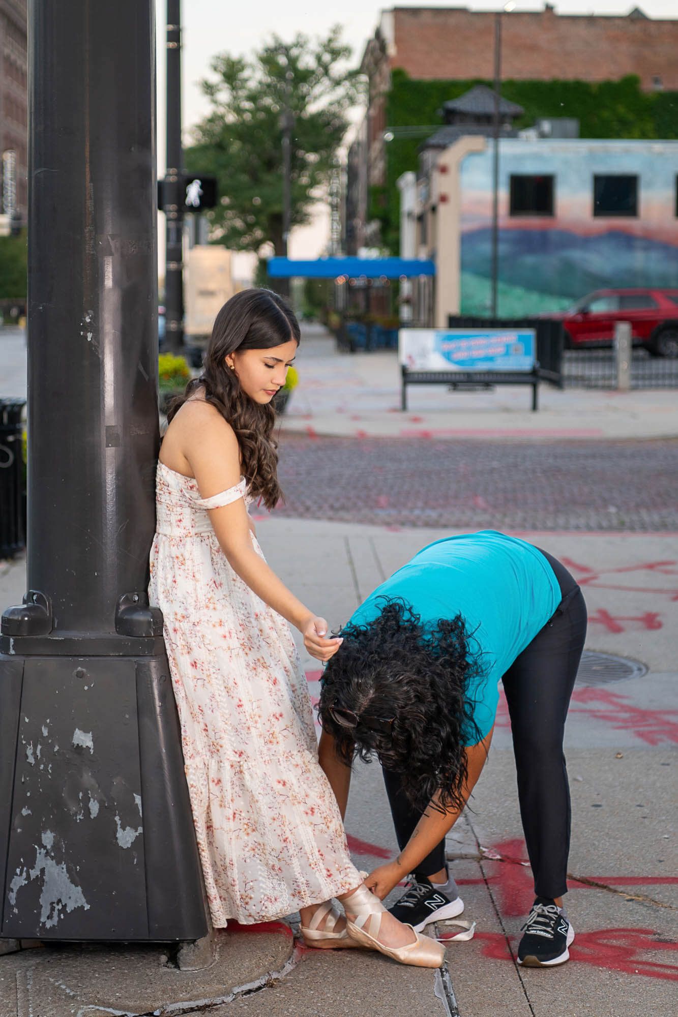 Two people in an urban setting playing a game of hopscotch on a brick paved sidewalk.