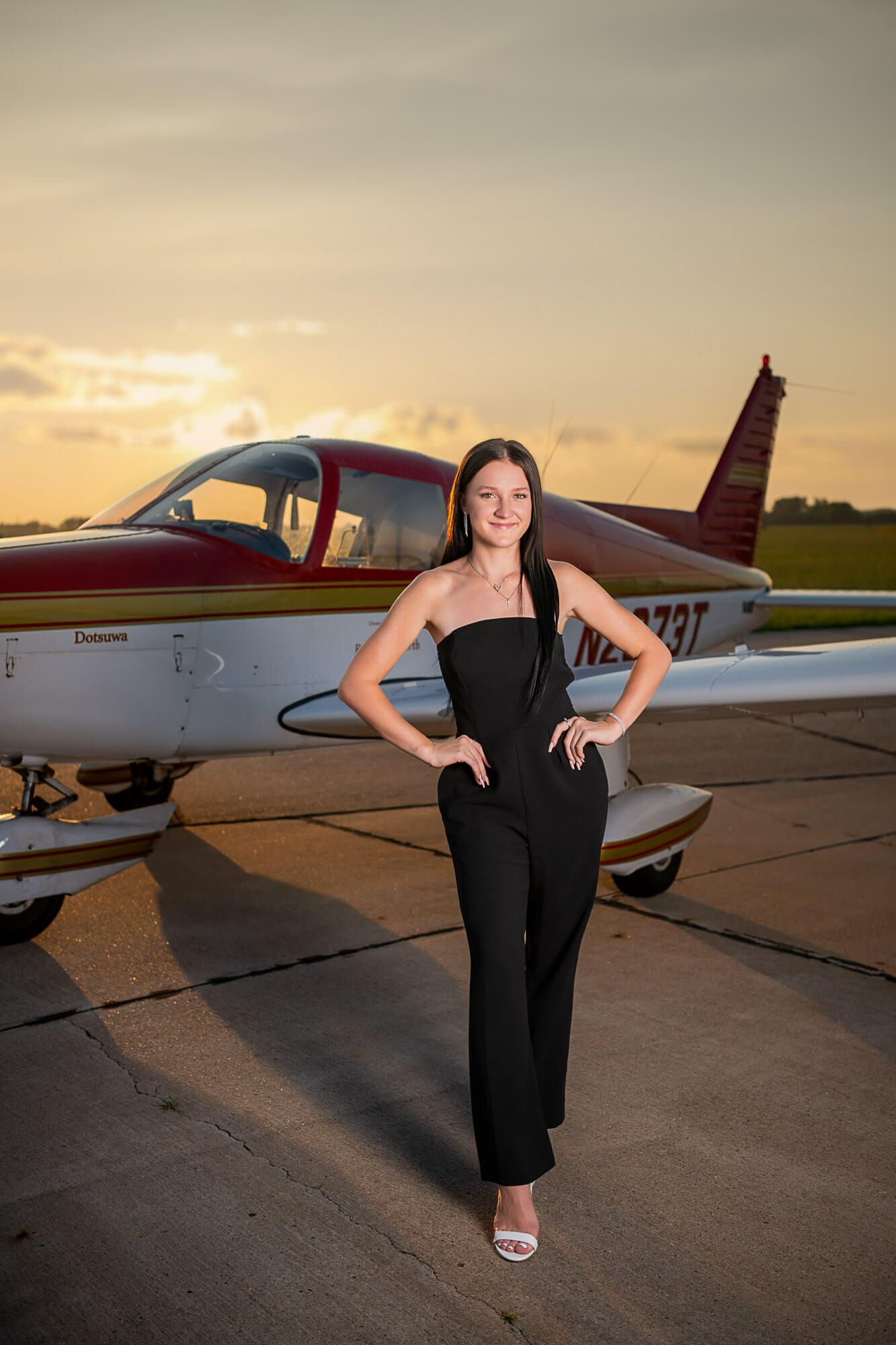 A small private aircraft parked on an airport tarmac during golden hour sunset.