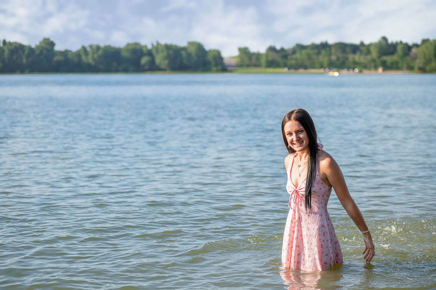 A series of photos showing someone in a pink dress enjoying a sunny day at a serene lake with trees in the background.