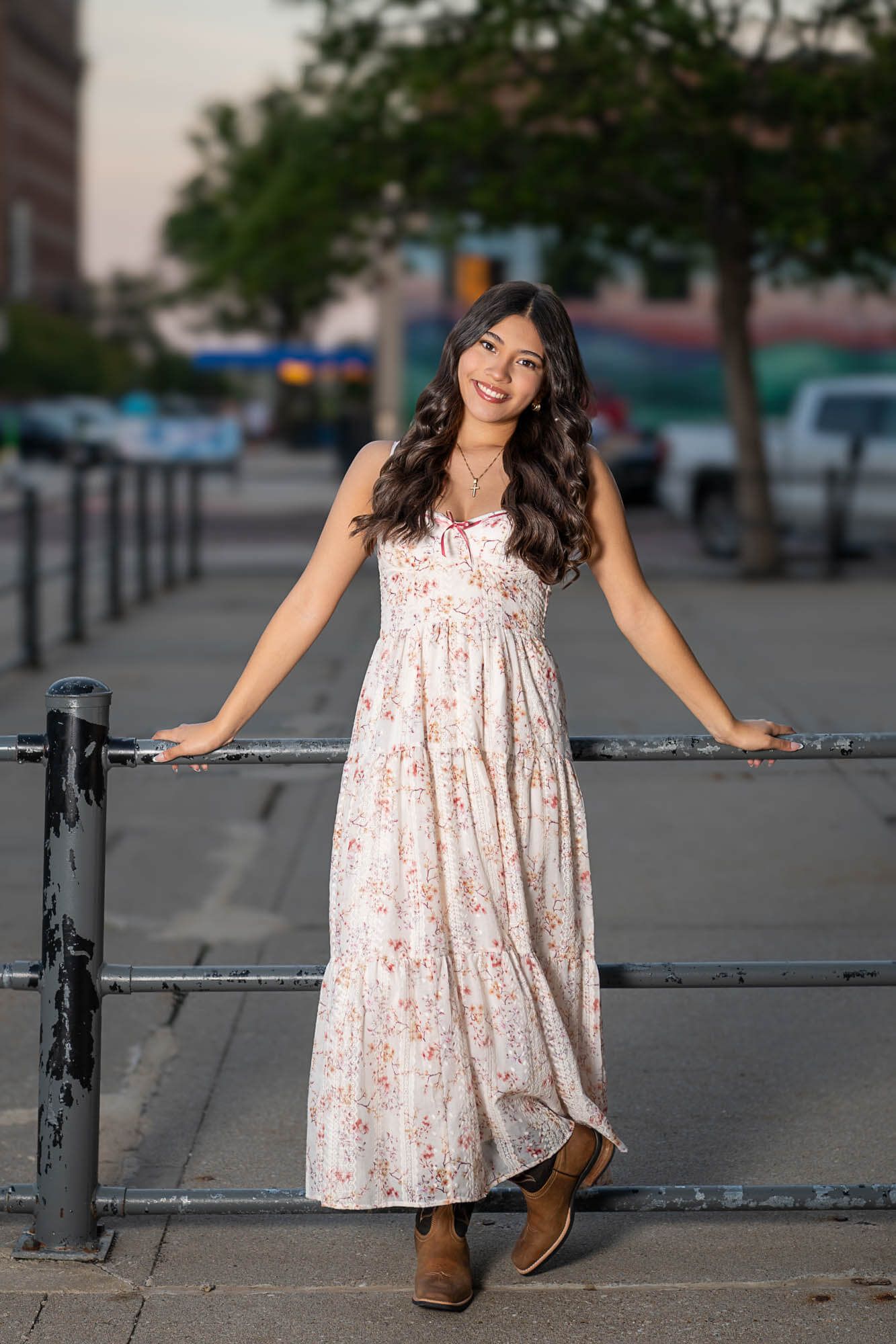 Series of playful poses in a floral dress against an urban backdrop with metal railings.