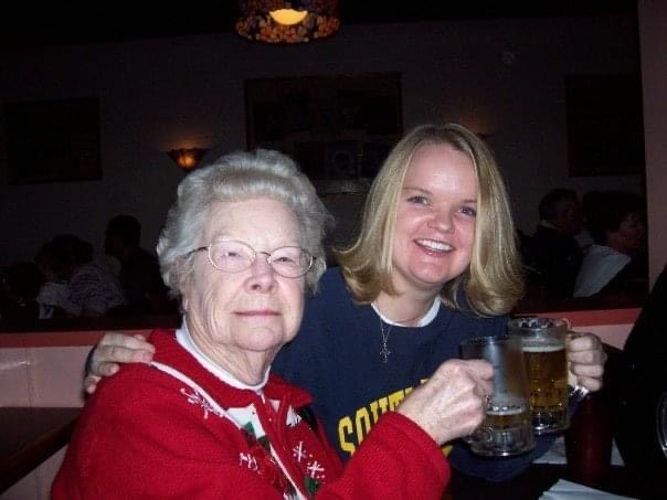 Two people smile together while enjoying drinks at a restaurant table with dimmed lighting in the background.