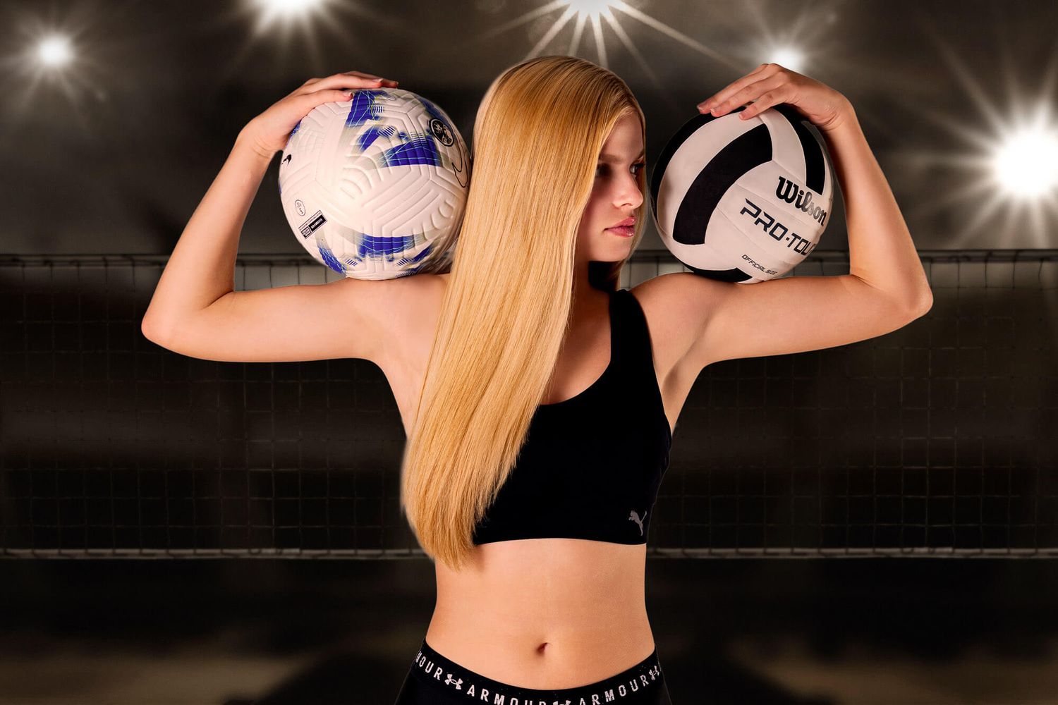 Blonde female athlete holding two volleyballs behind her head in a sports arena with dramatic lighting.