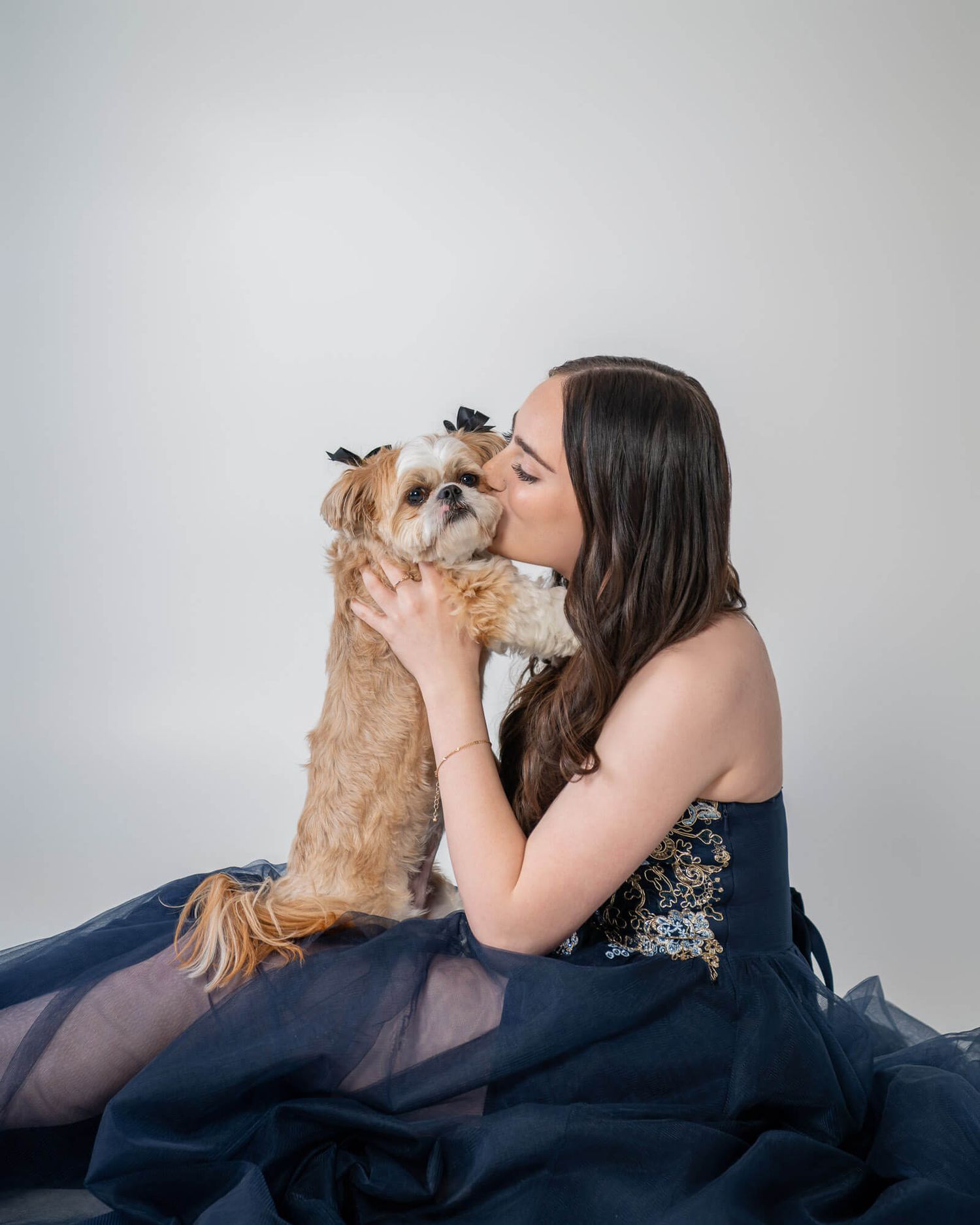 A series of photos showing a tender moment between a person in a dark dress and a small Shih Tzu dog on a couch.