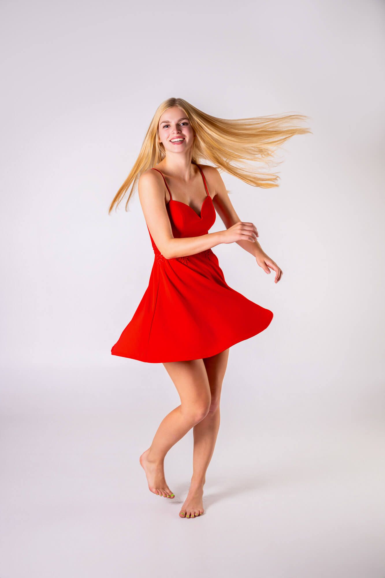 Dynamic dance poses in a flowing red dress against a white backdrop showcase graceful movement and energy.