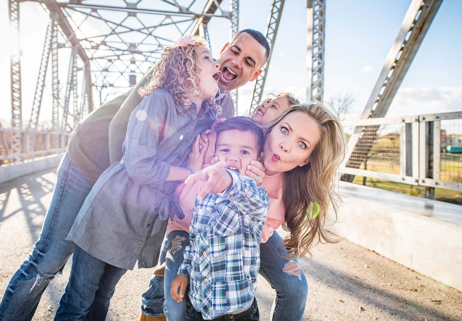 Candid family moments captured on an old steel bridge during a bright afternoon photoshoot.