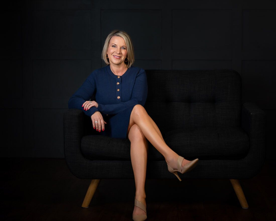 Professional studio portrait series showing a person in a navy dress seated against a dark background.