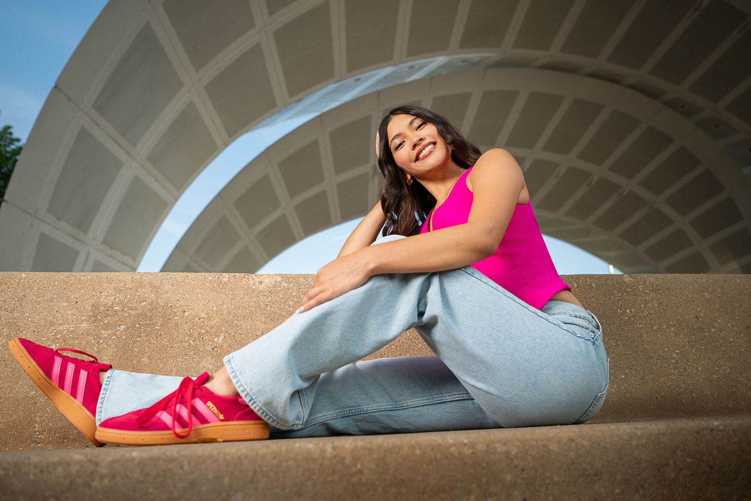 Artistic photo series showing poses against a curved architectural backdrop with pink and denim outfit.
