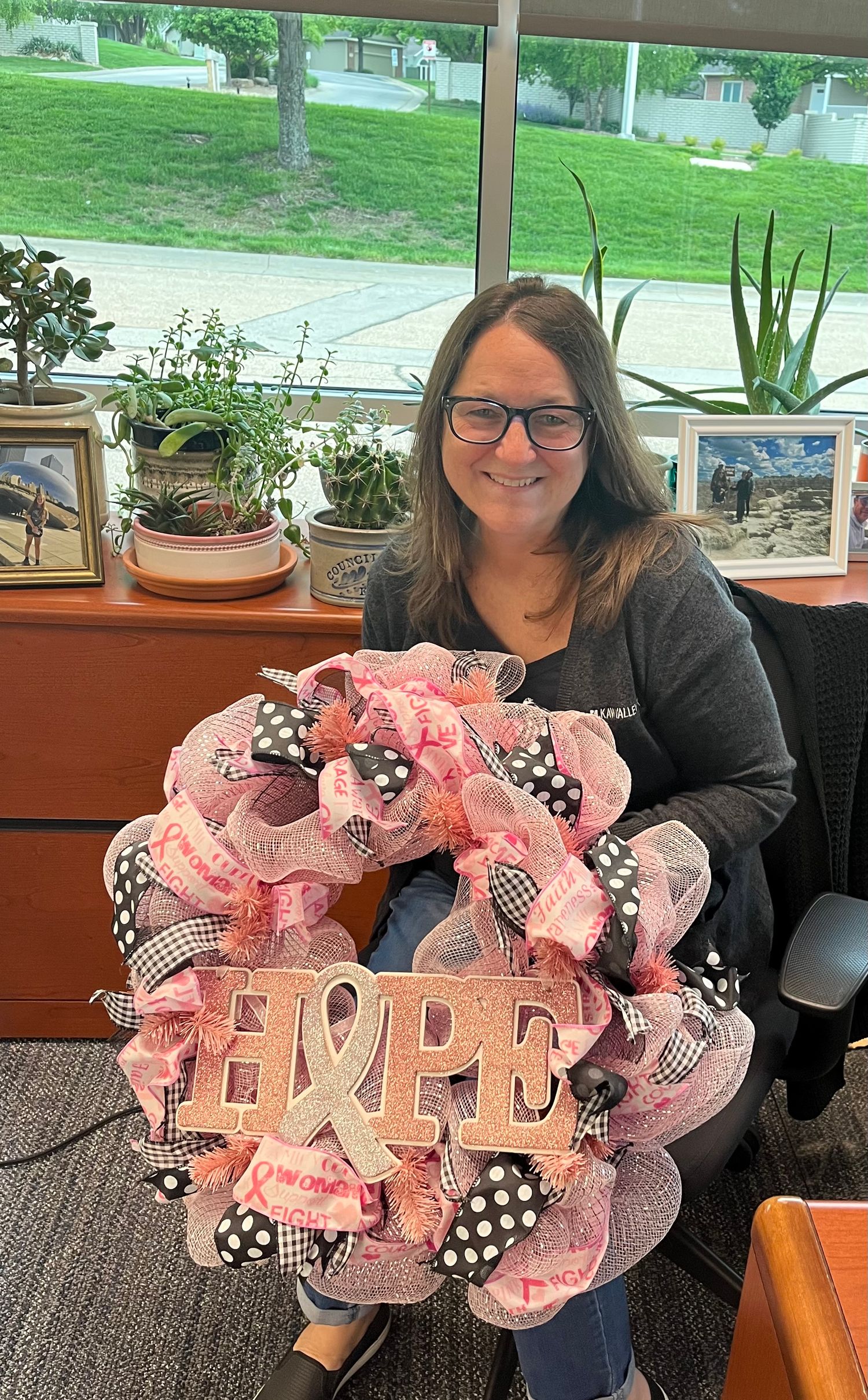 A pink, black and white Hope-themed decorative mesh wreath with polka dot ribbons displayed indoors by a window.