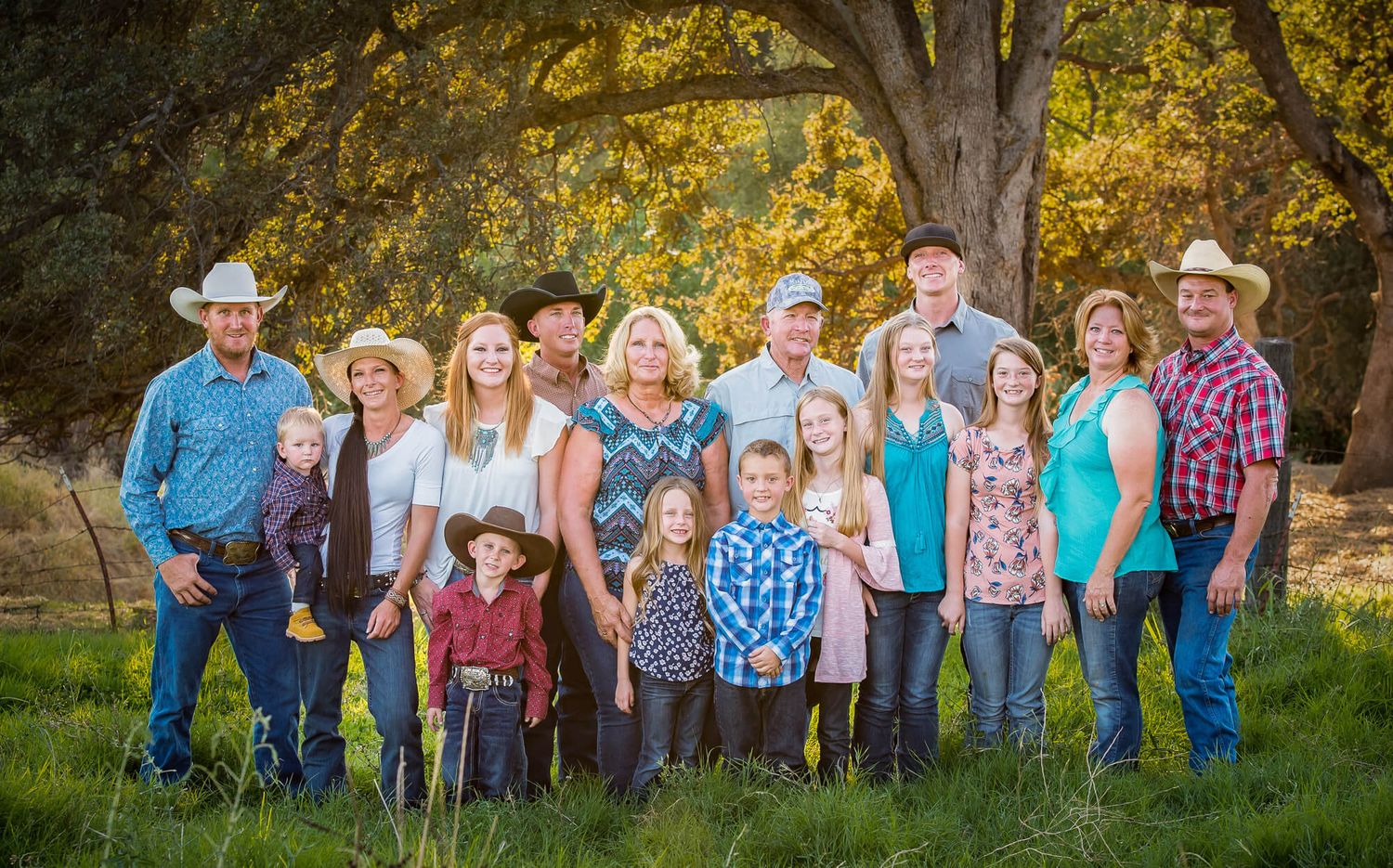 A group of people in western attire gather outdoors for a casual portrait session in a natural setting.