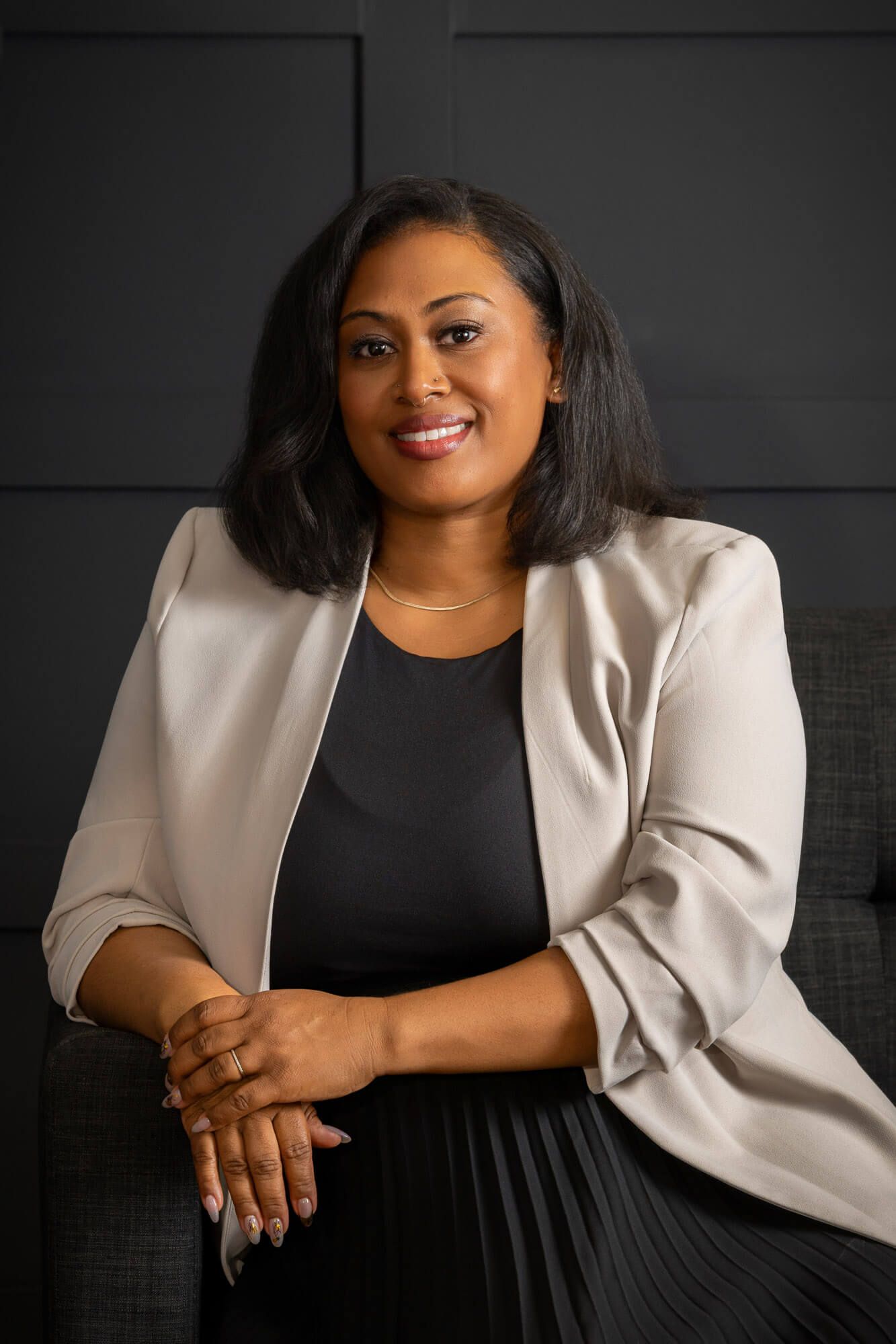 Professional portrait series showing a person in a black dress and cream blazer against a dark background.