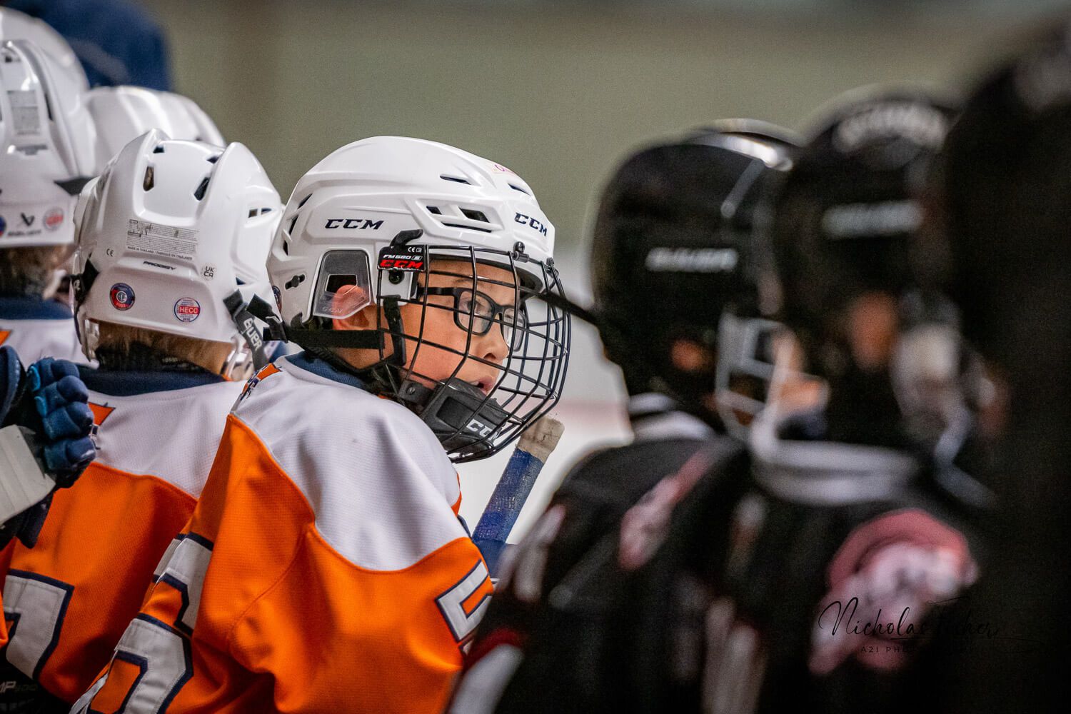 Hockey players in orange and white jerseys celebrate together along the boards during a game.