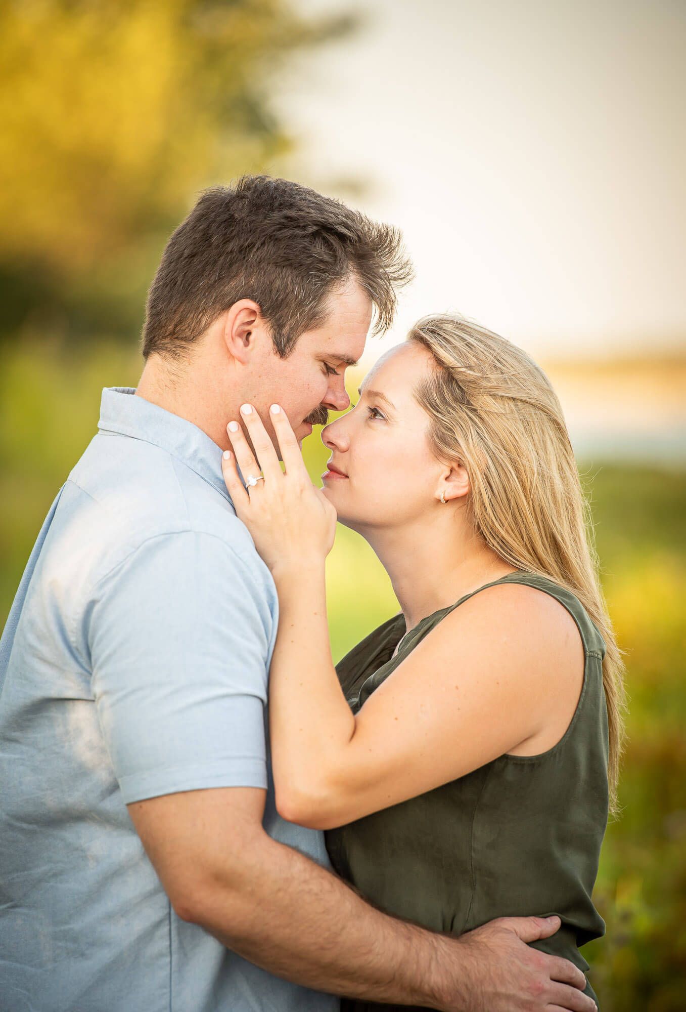 A romantic couple embraces outdoors in warm golden sunlight during a tender moment.