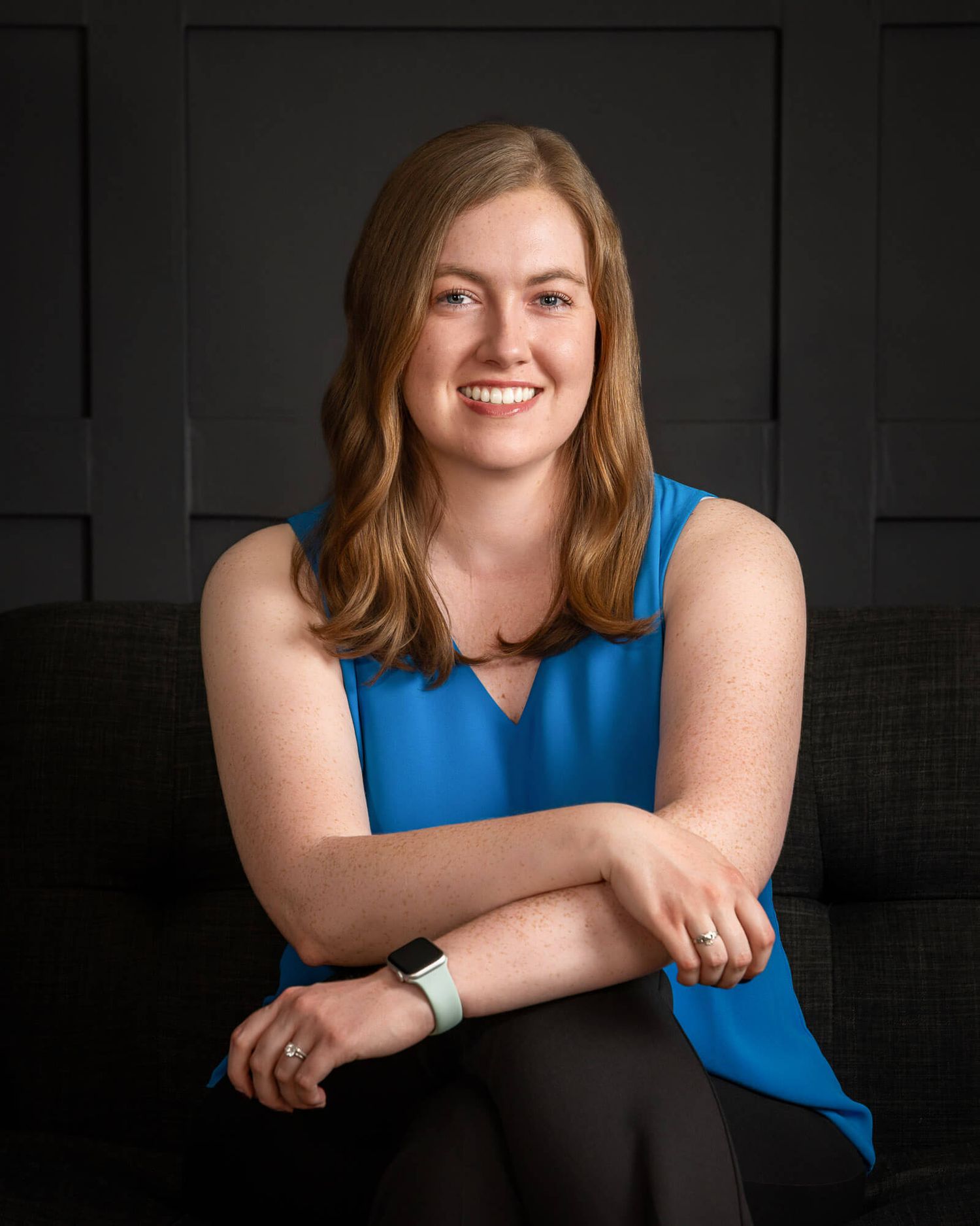Professional headshot series against dark background showing casual pose in blue sleeveless top.