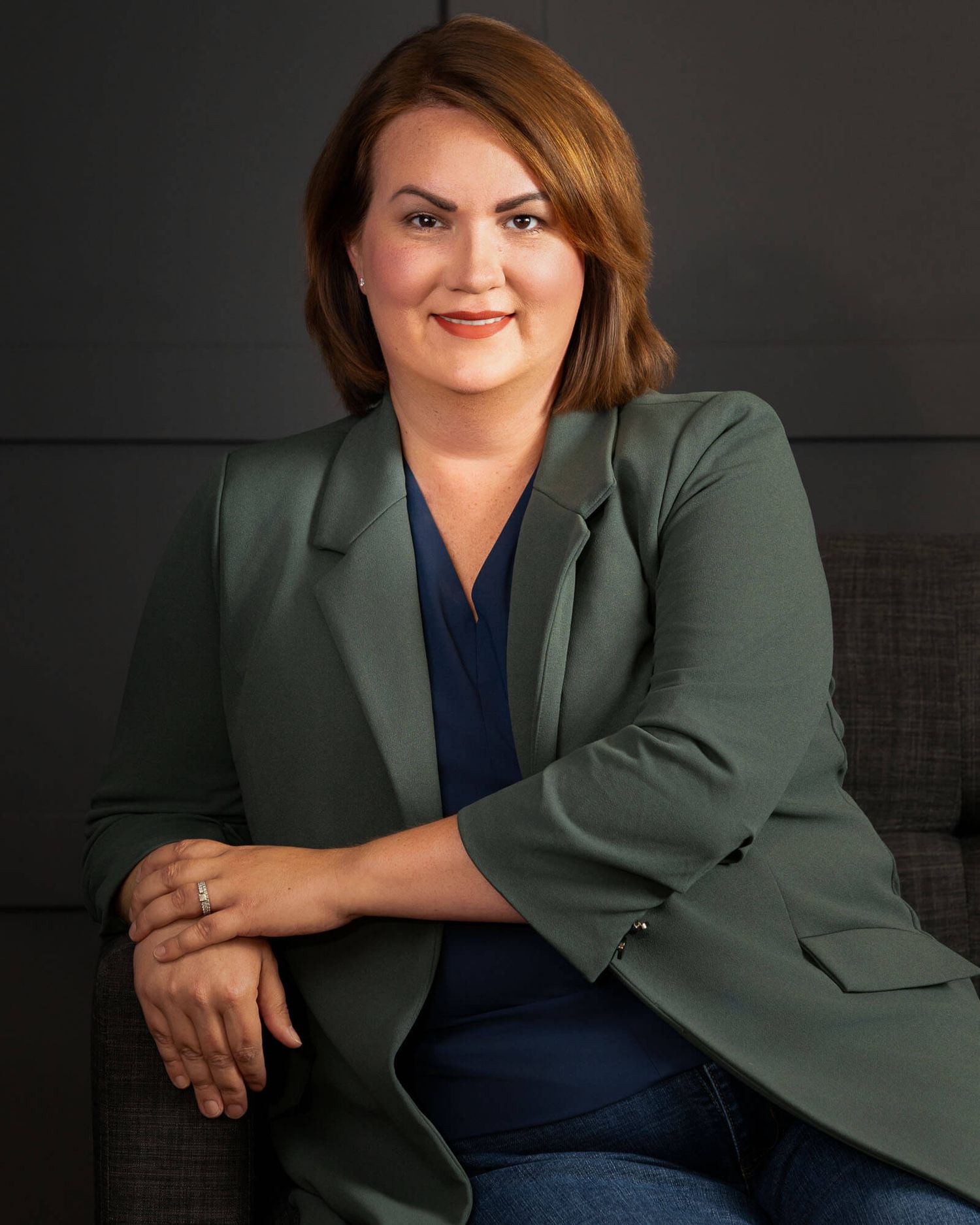 Studio portraits against dark background featuring relaxed poses in green blazer and navy top.