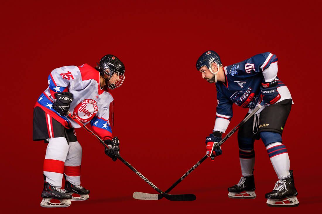 Hockey players battle for the puck during an intense face-off on red ice.