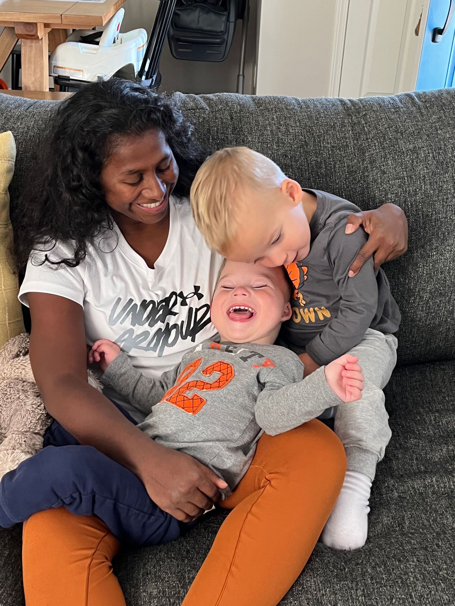 A joyful moment captured on a gray couch showing expressions of pure happiness and laughter.