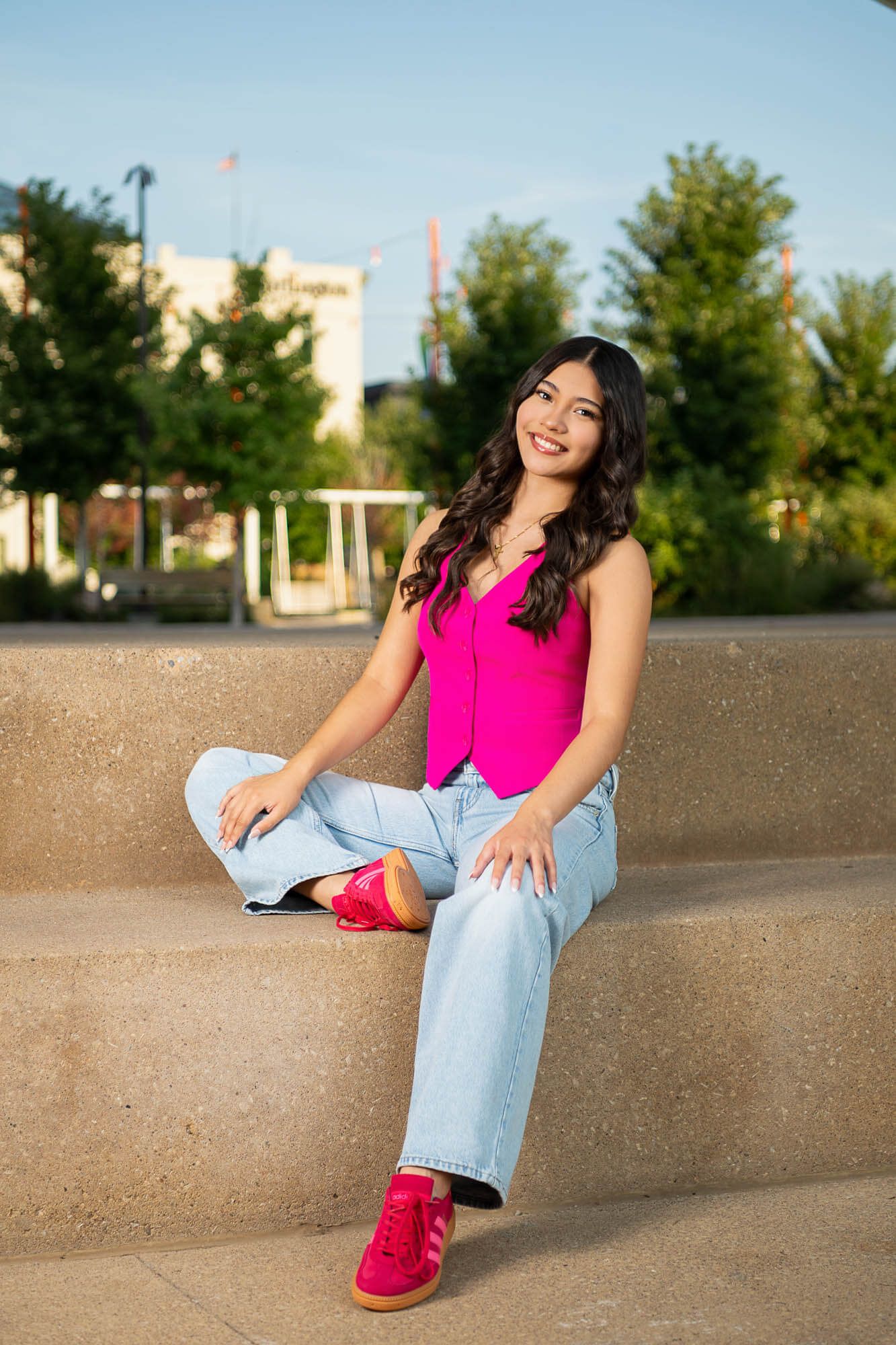 Casual urban portraits against concrete wall wearing pink top and light jeans with bright sneakers.