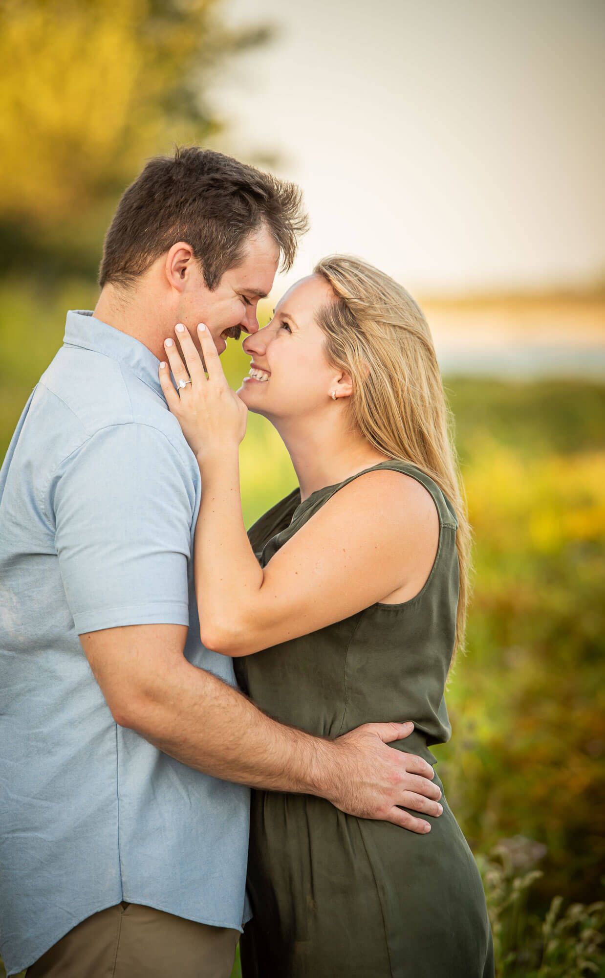 A couple shares a tender romantic moment in a sunlit meadow during golden hour.