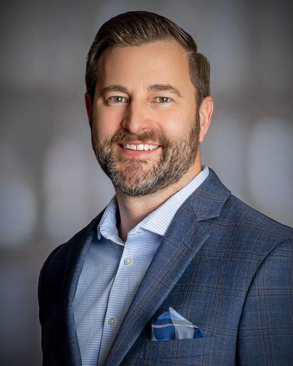 Business headshots featuring person in blue plaid jacket and white shirt against grey backdrop.