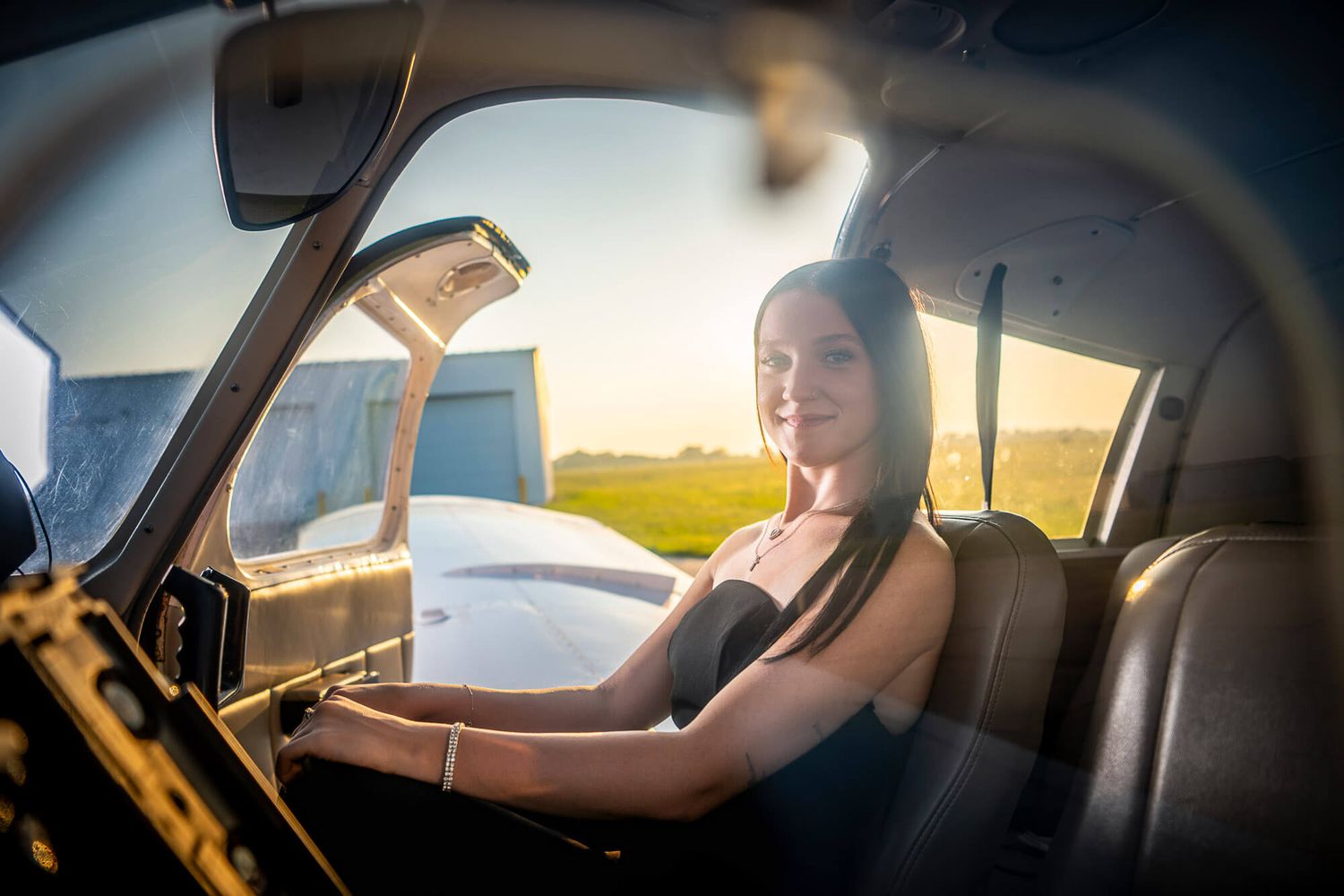 Person driving a car during golden hour with sun rays illuminating the interior through the window.