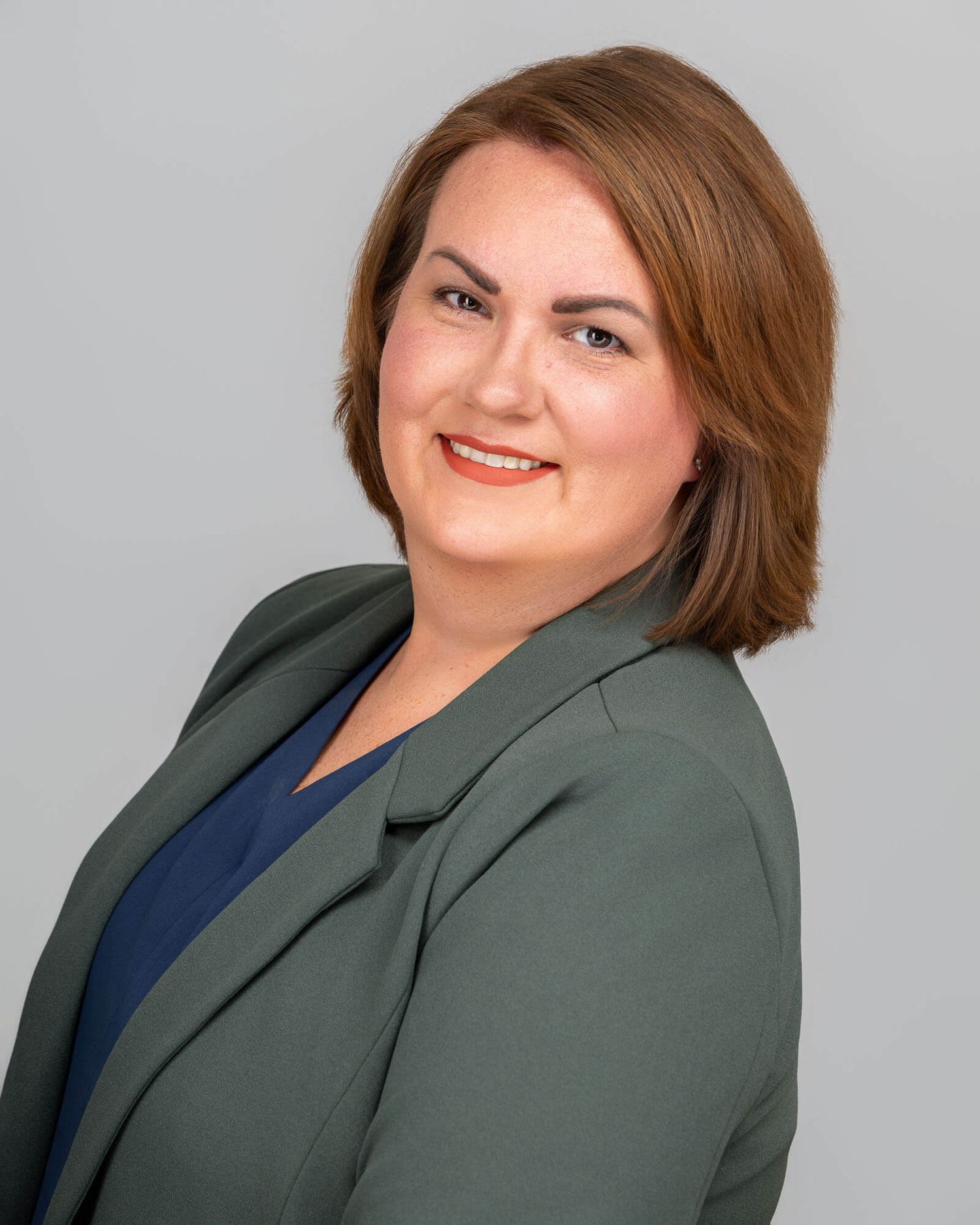 Series of professional portraits showing person in green blazer and navy top against light backdrop.