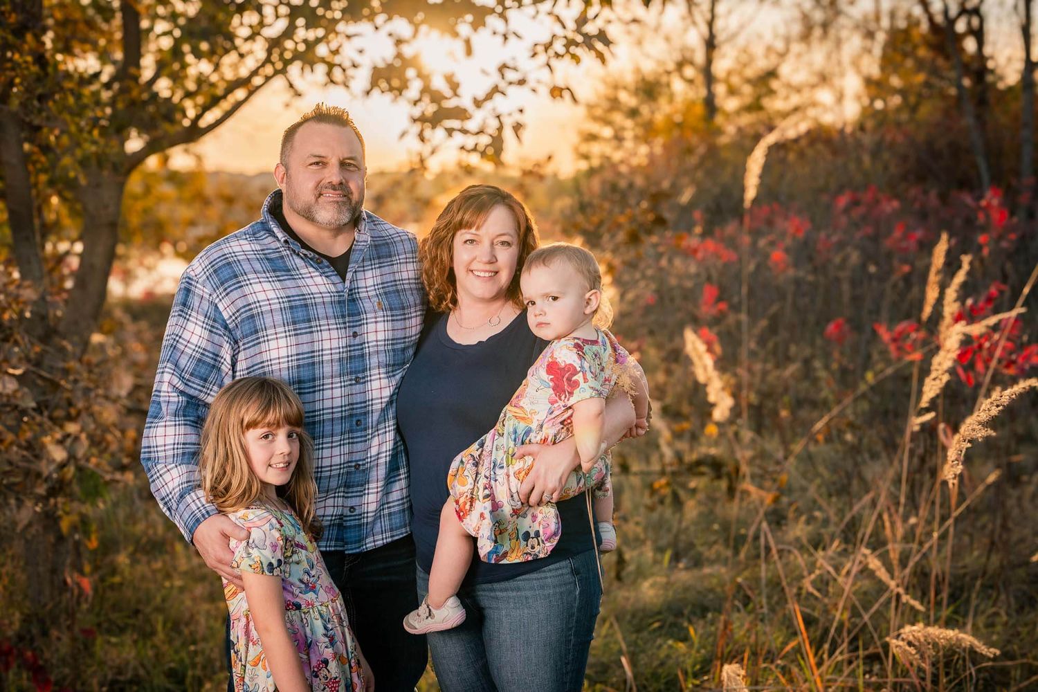 Family poses together in a series of outdoor autumn portraits at sunset with golden light filtering through trees.