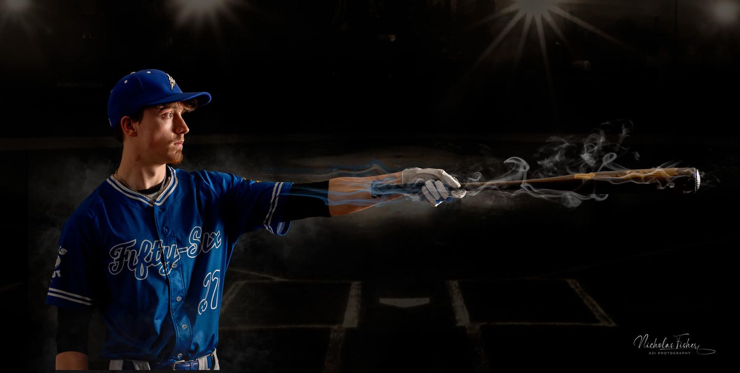 Baseball player in blue Toronto Blue Jays uniform dramatically pointing a smoking bat in a dark, atmospheric studio setting.