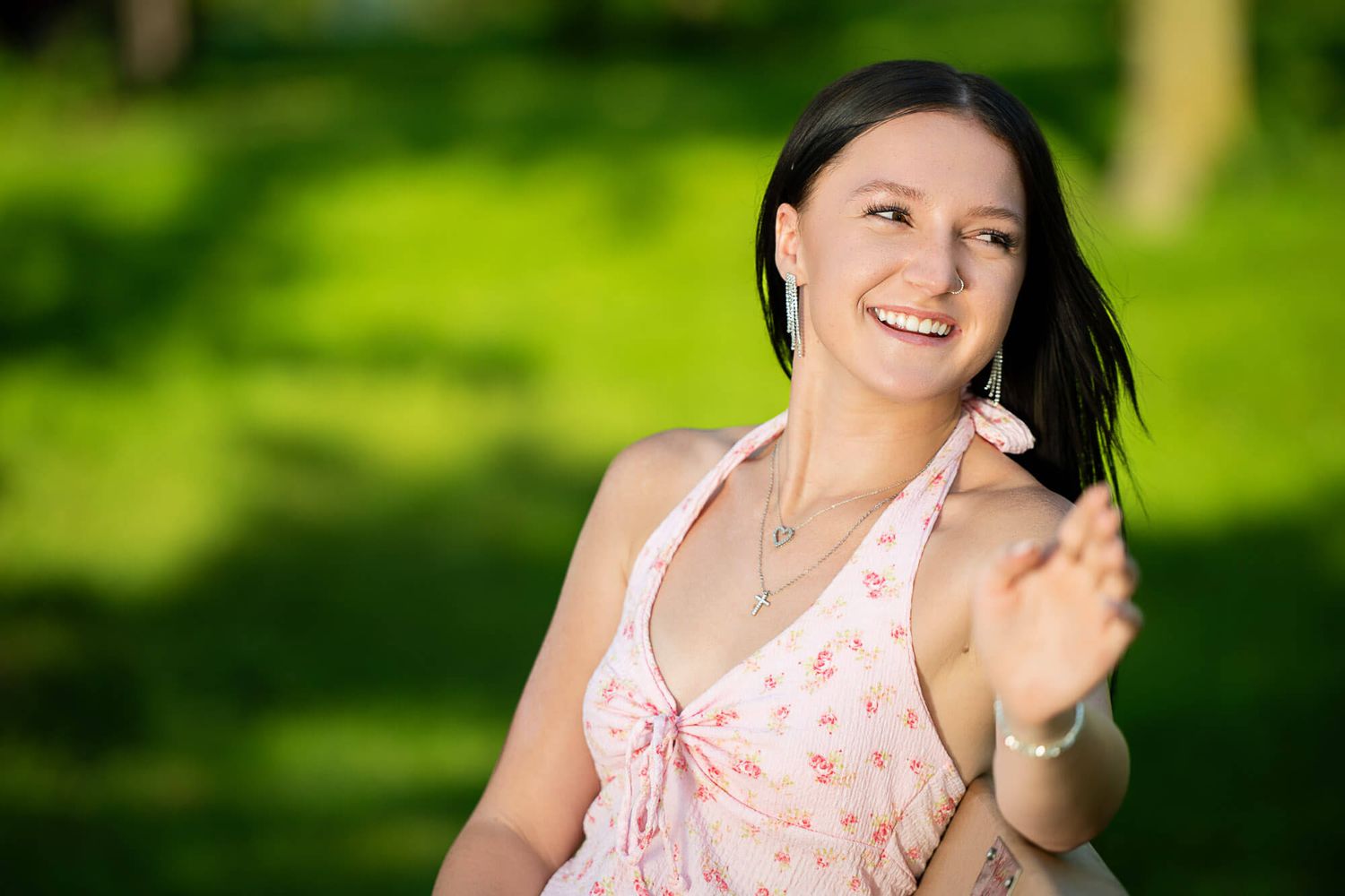 Senior girl in Norfolk, near Omaha, looking into the distance while sitting on a bench at a park.