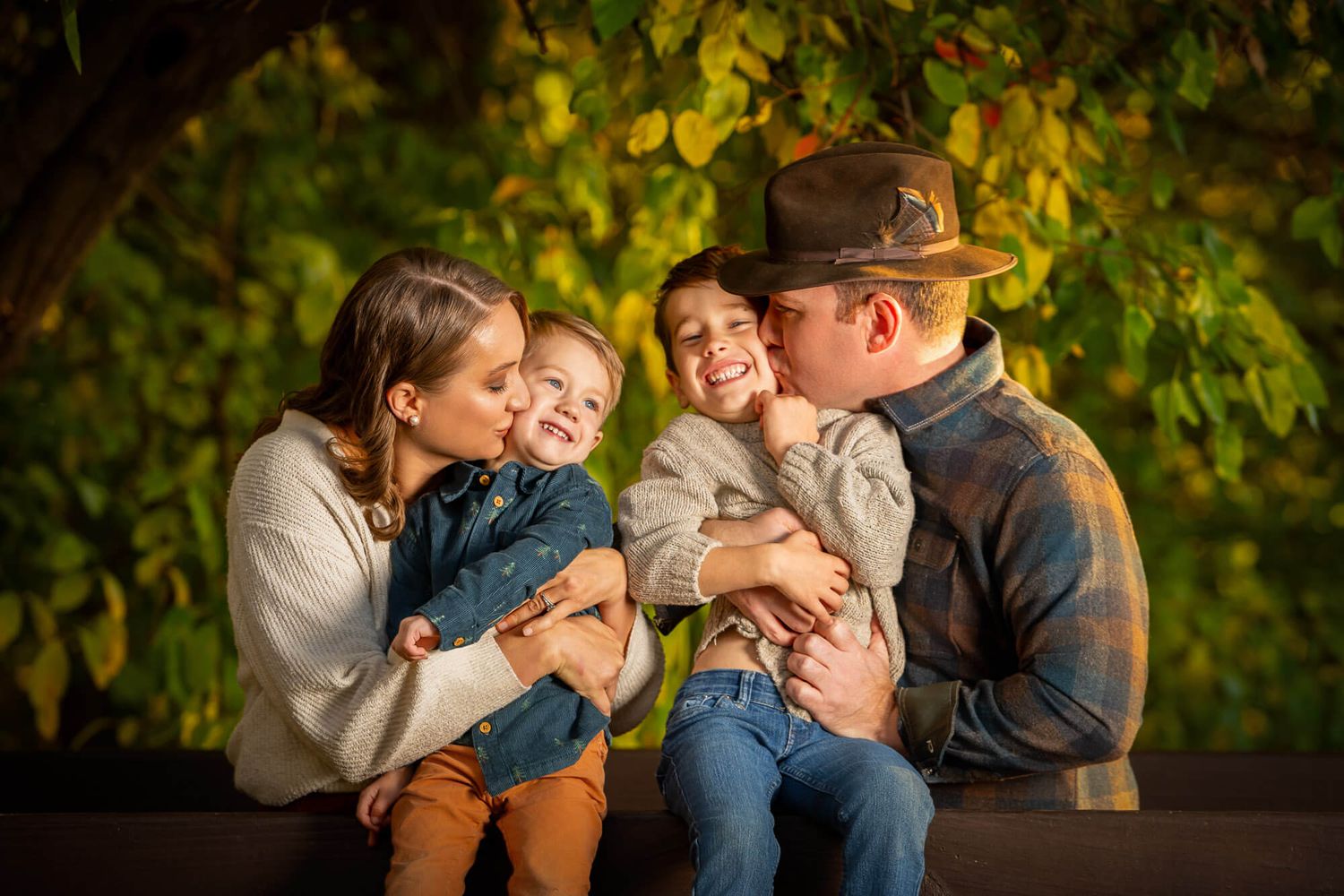A loving family shares tender moments together while sitting outdoors surrounded by autumn foliage.