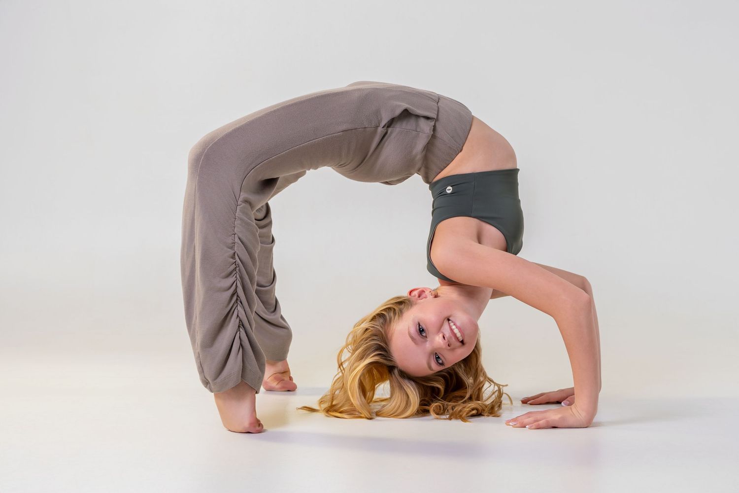 Omaha Senior Photography - Photographer in Omaha - Yoga practitioner performing a backbend bridge pose in gray leggings on white background.