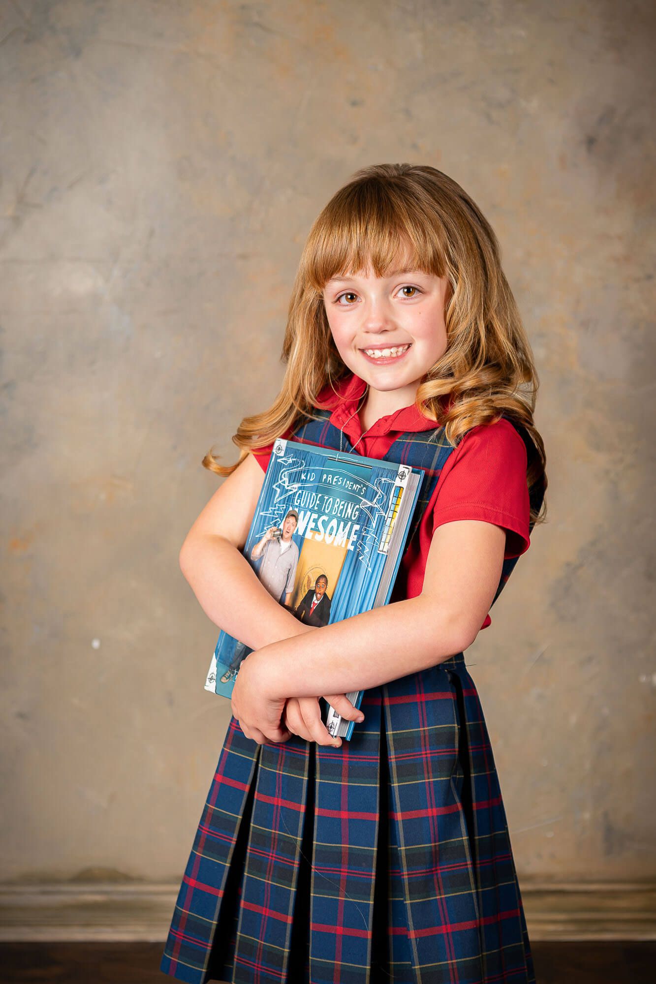Multiple poses of a student embracing books while wearing a plaid uniform dress.
