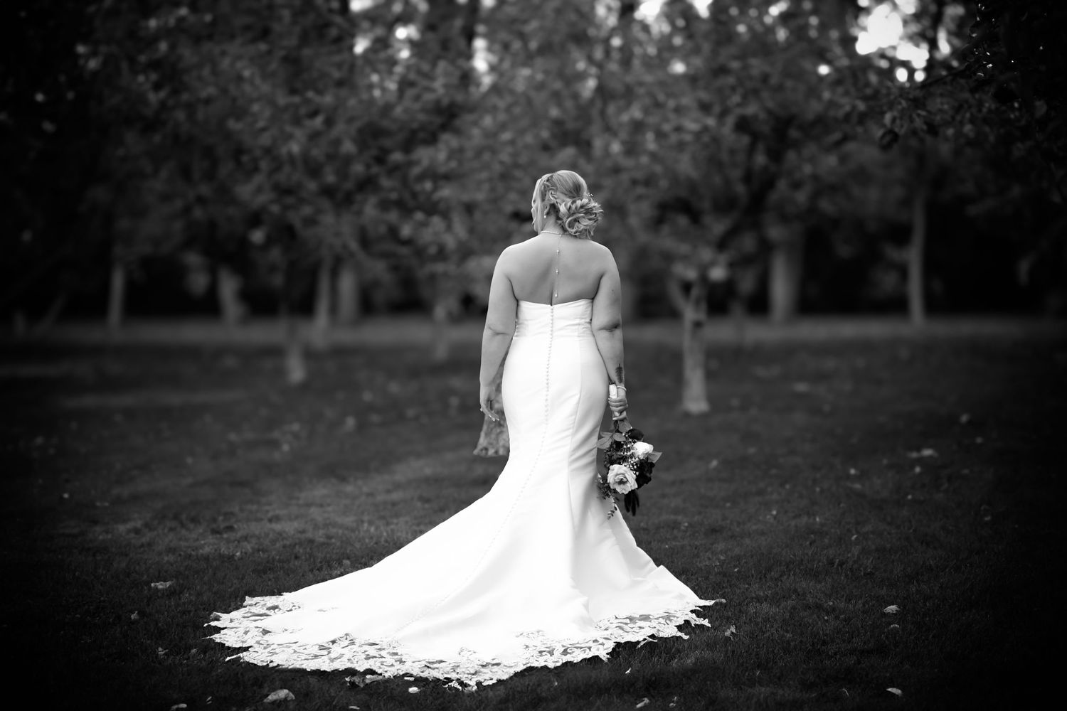 A romantic black and white wedding photo series showing elegant bridal poses and flowing white dress details in an outdoor setting.